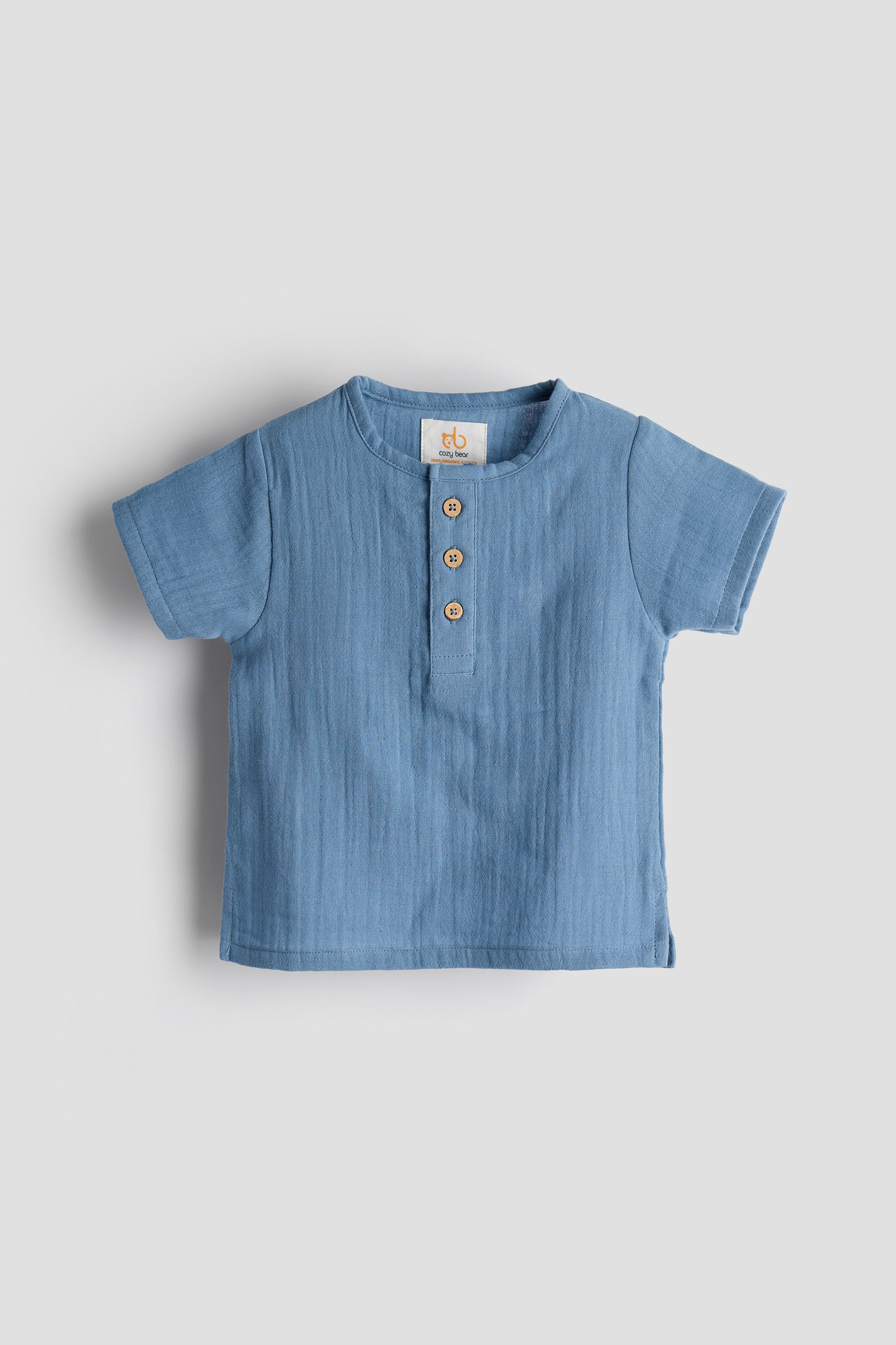 Blue baby shirt with buttons on a light gray background