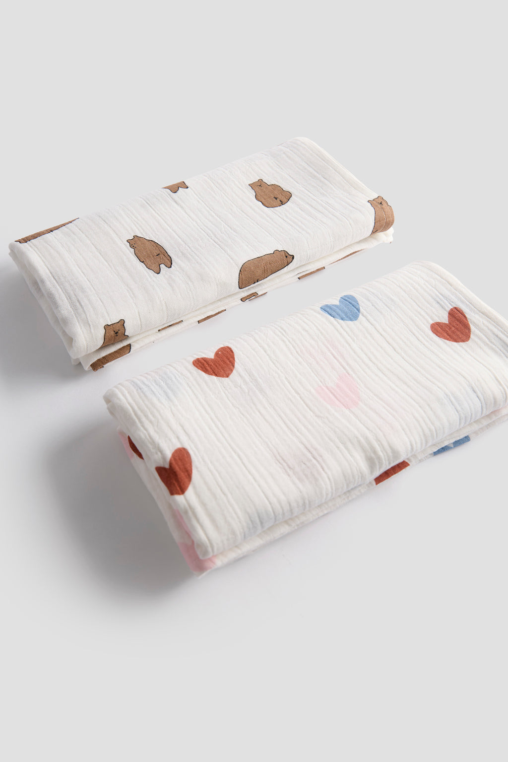 Two baby blankets with heart patterns on a light gray background