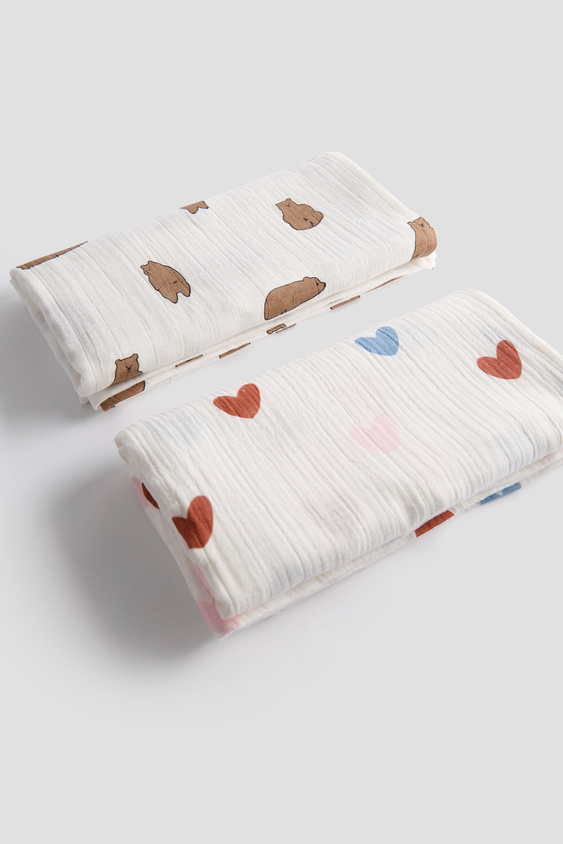 Two baby blankets with heart patterns on a light gray background