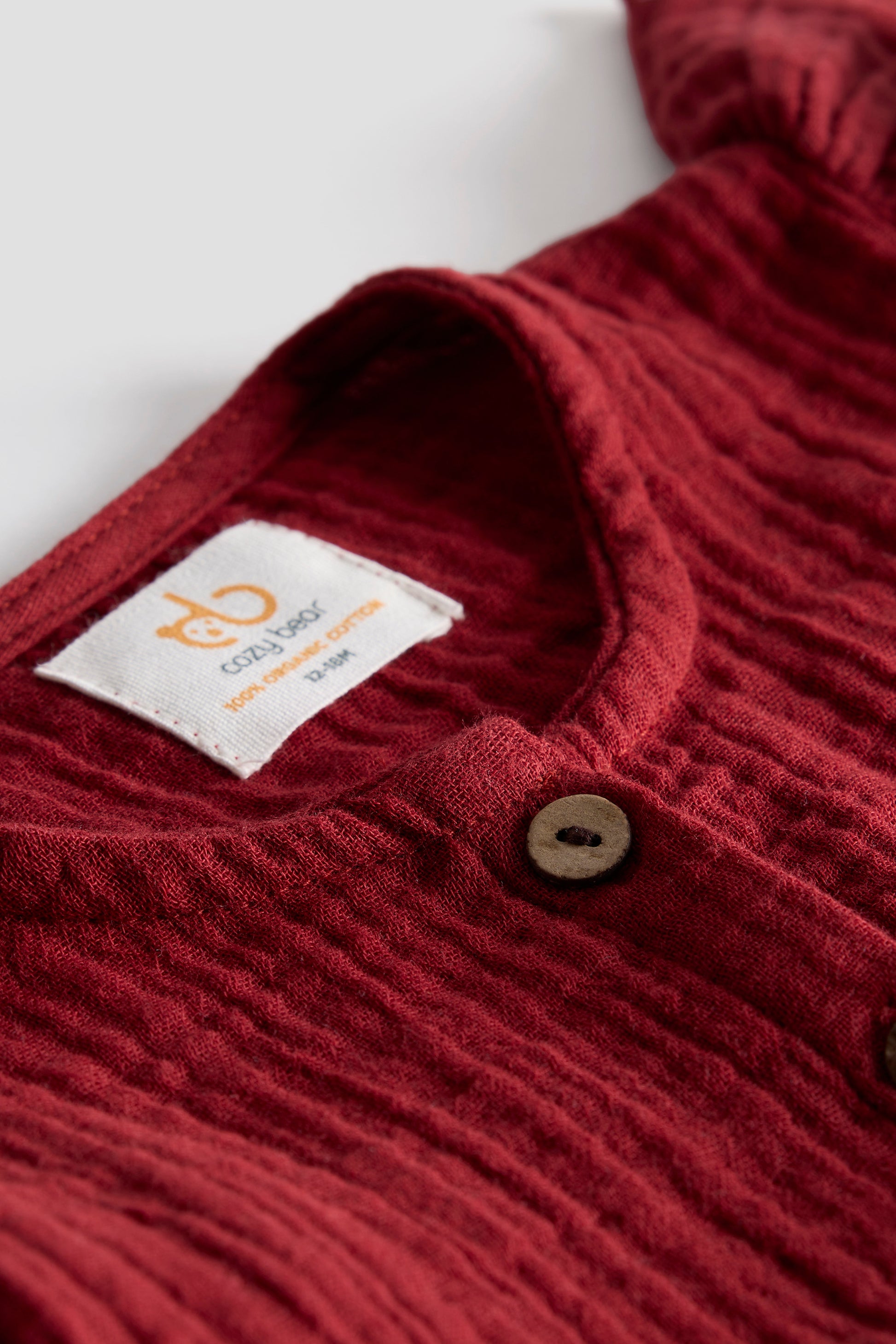 Close-up of a red textured garment with a brand label on a white background