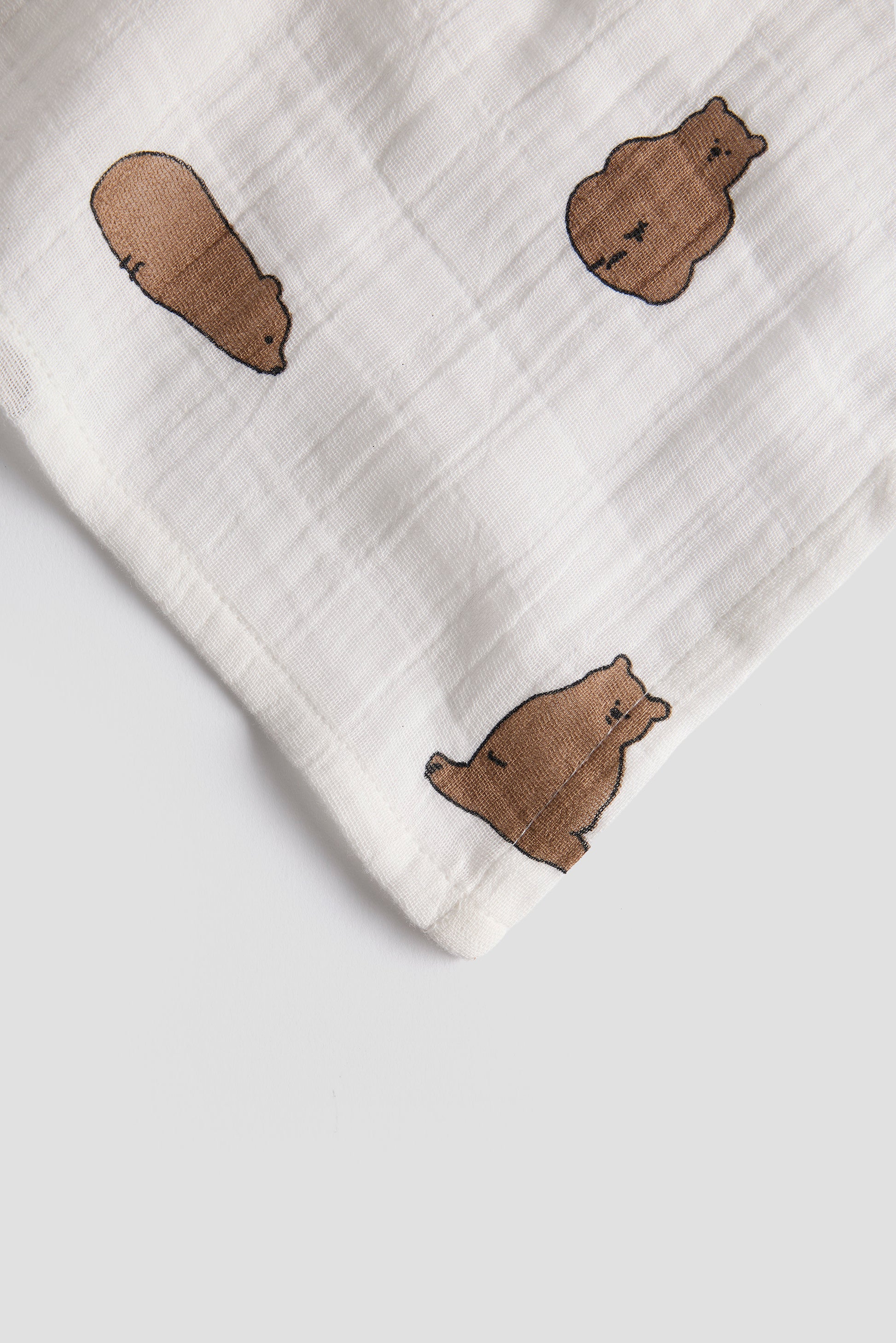 White fabric with brown bear illustrations on a light gray background