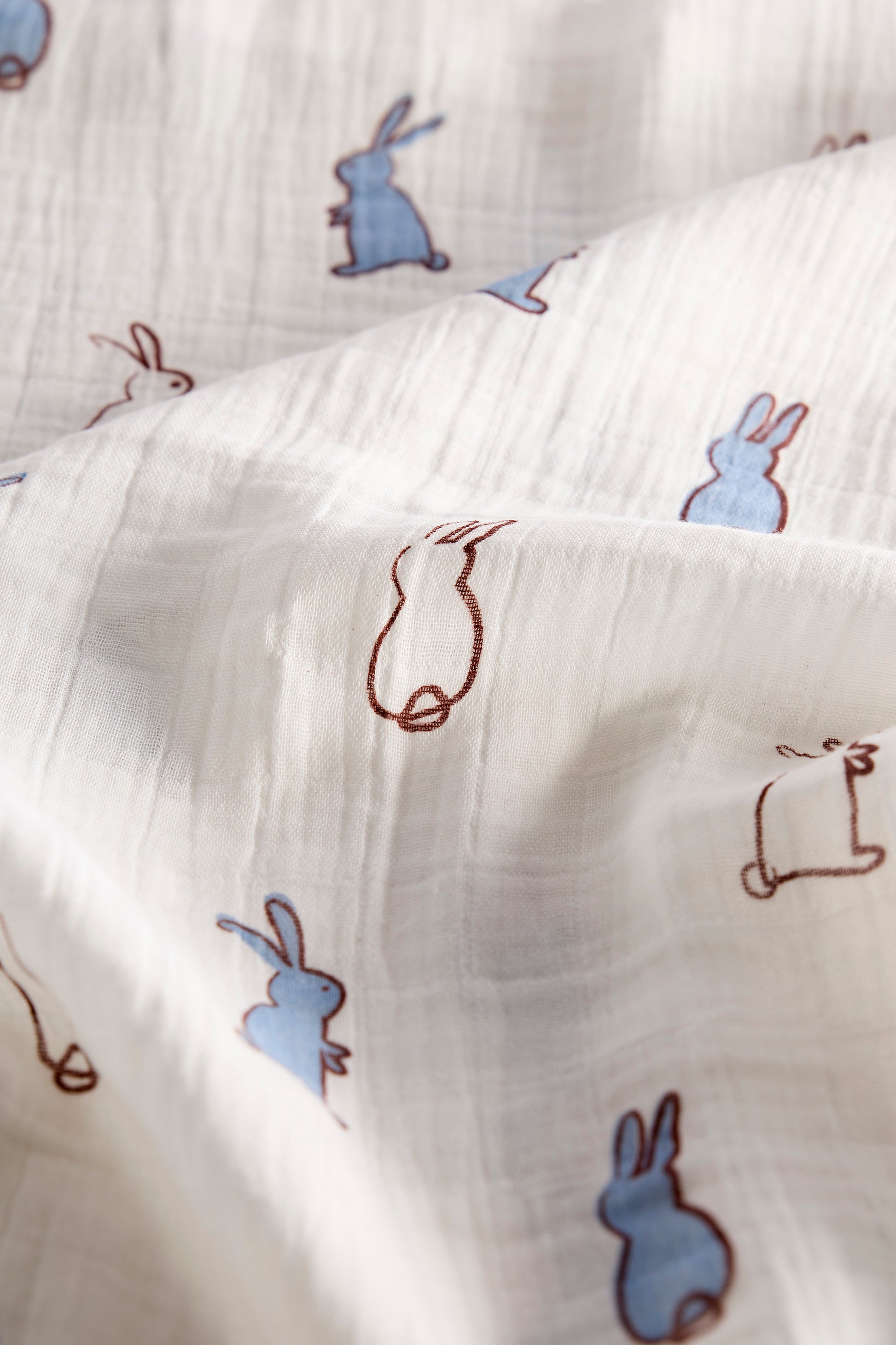 Close-up of fabric with blue and brown rabbit illustrations.