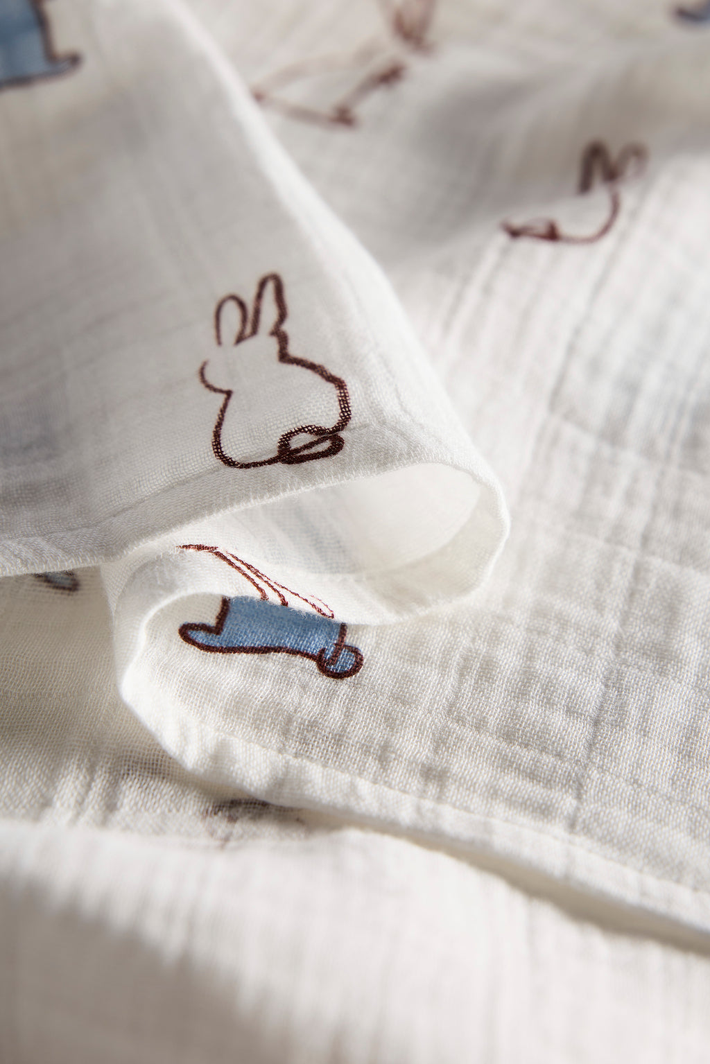 Close-up of white fabric with embroidered bunny designs on a light background
