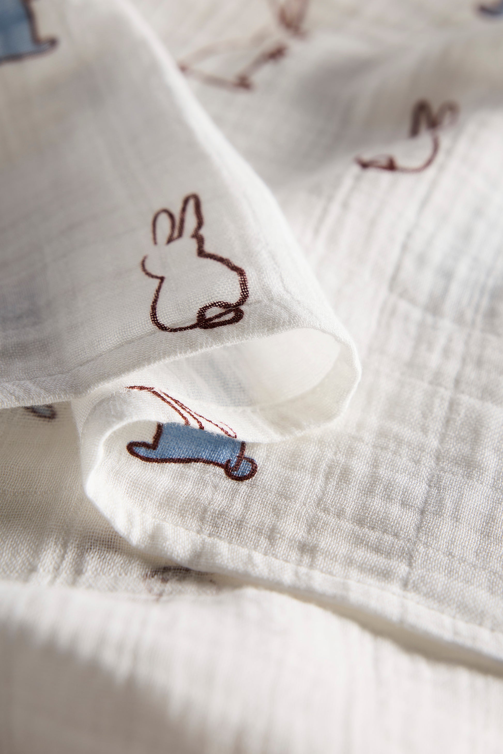 Close-up of white fabric with embroidered bunny designs on a light background