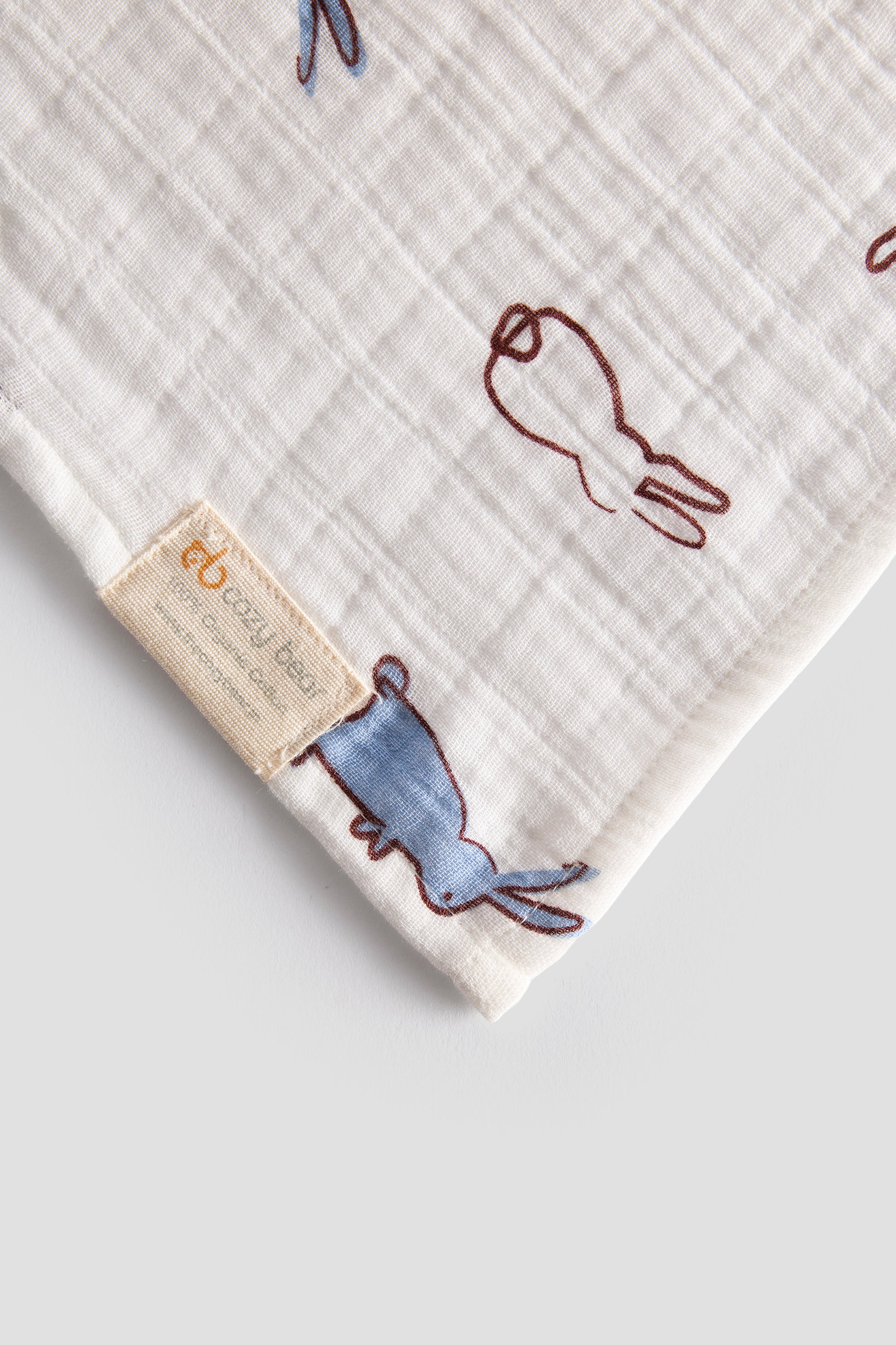 Baby blanket with embroidered designs and a label on a light gray background