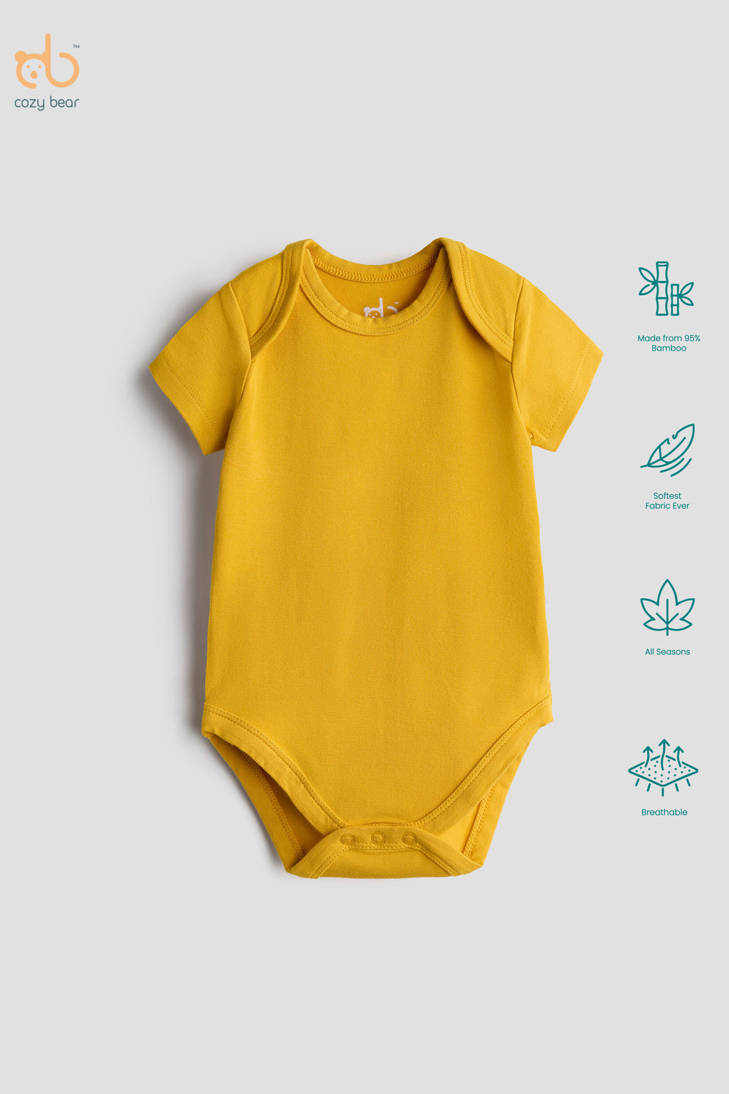 A yellow short-sleeve baby bodysuit laid flat on a light gray background, with a small white 'cozy bear' logo printed inside the collar. To the right are four teal feature icons for bamboo, organic cotton, OEKO-TEX, and breathable fabric.
