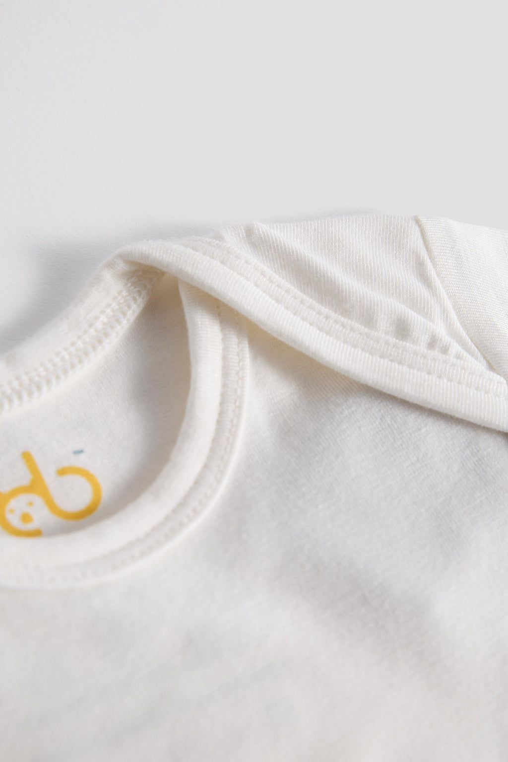 White onesie showing the neck part focusing the brand logo and showing the shoulder 