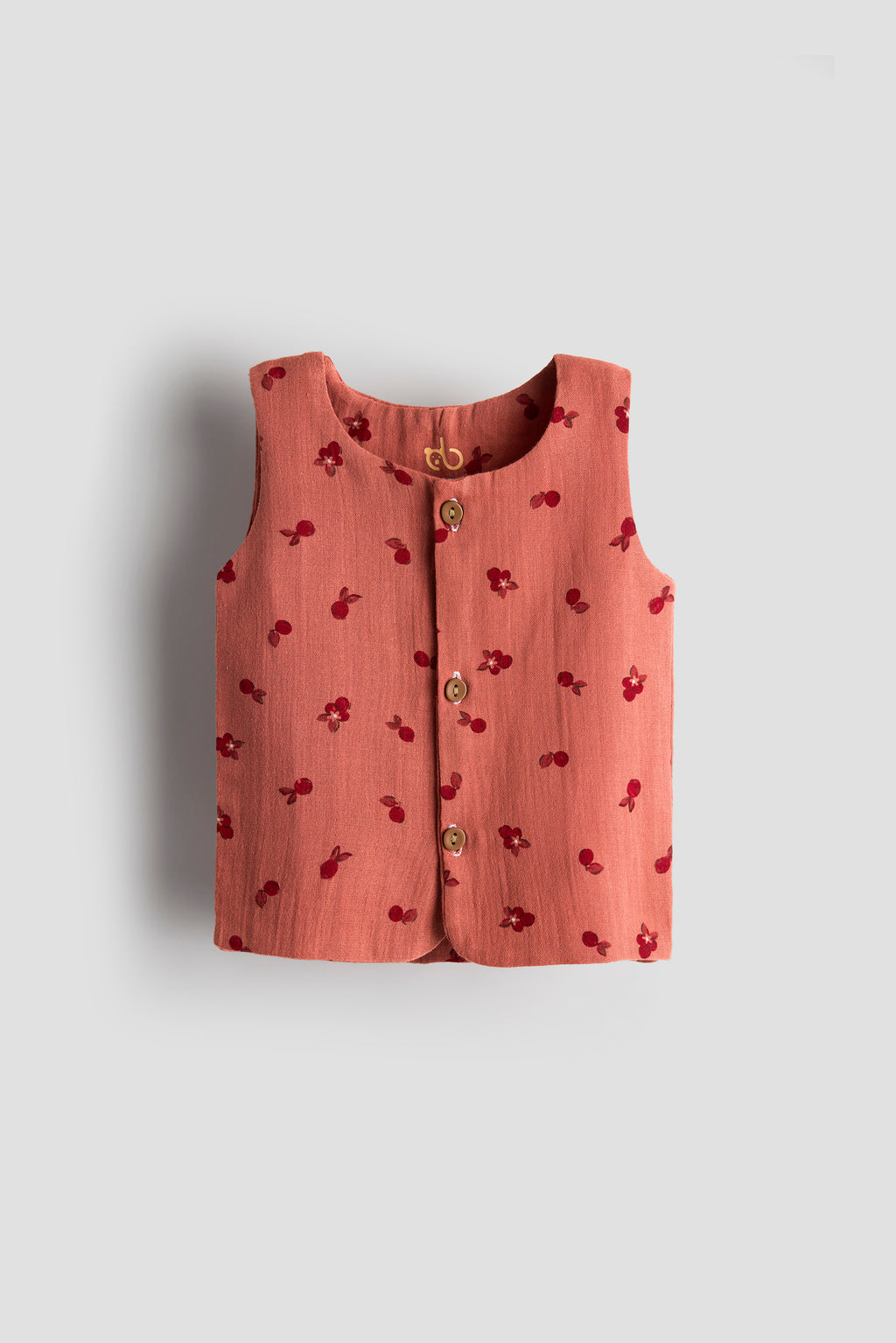 Pink sleeveless top with cherry pattern on a light gray background