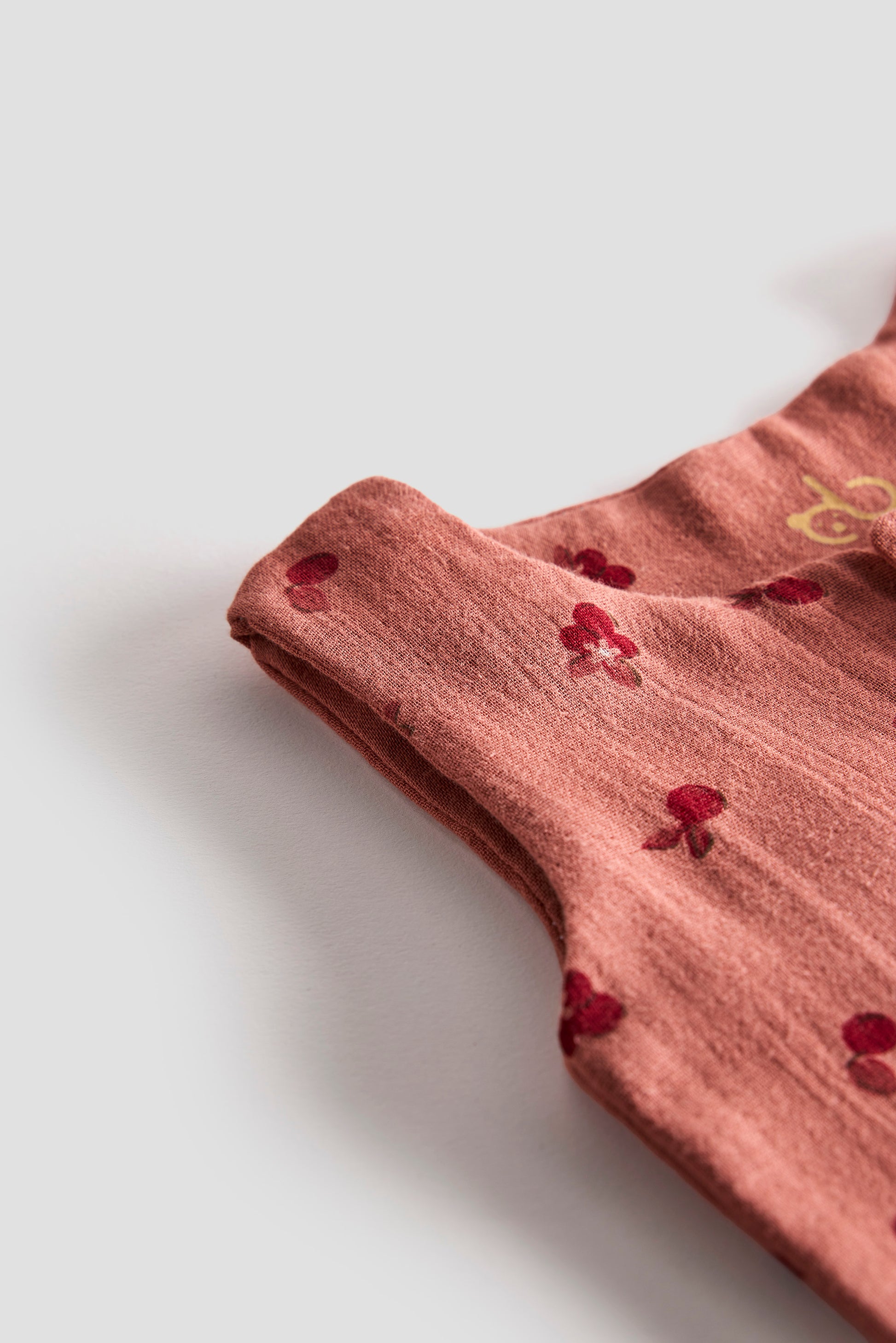 Folded pink fabric with red floral patterns on a white background