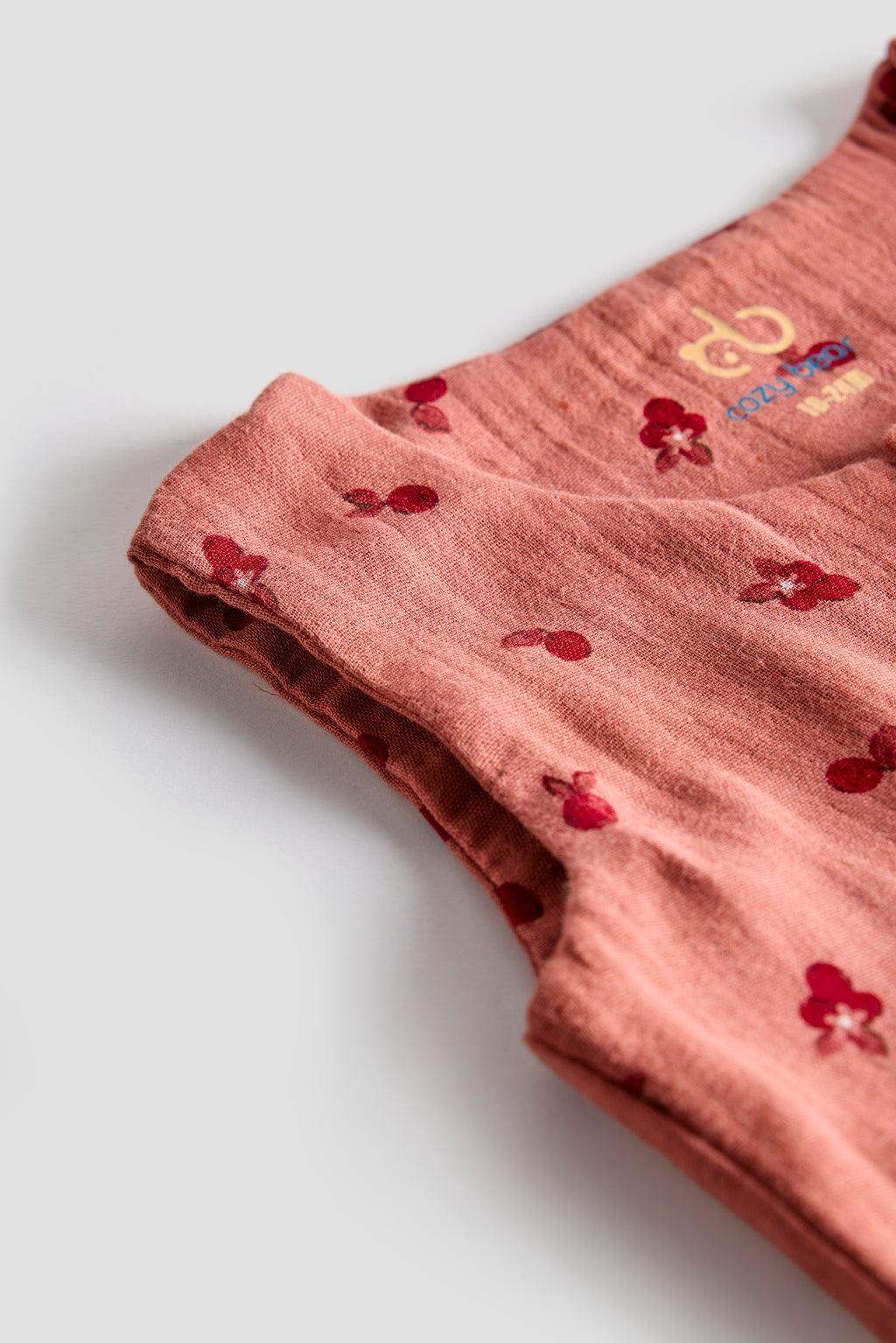 Pink fabric with red floral patterns on a light gray background
