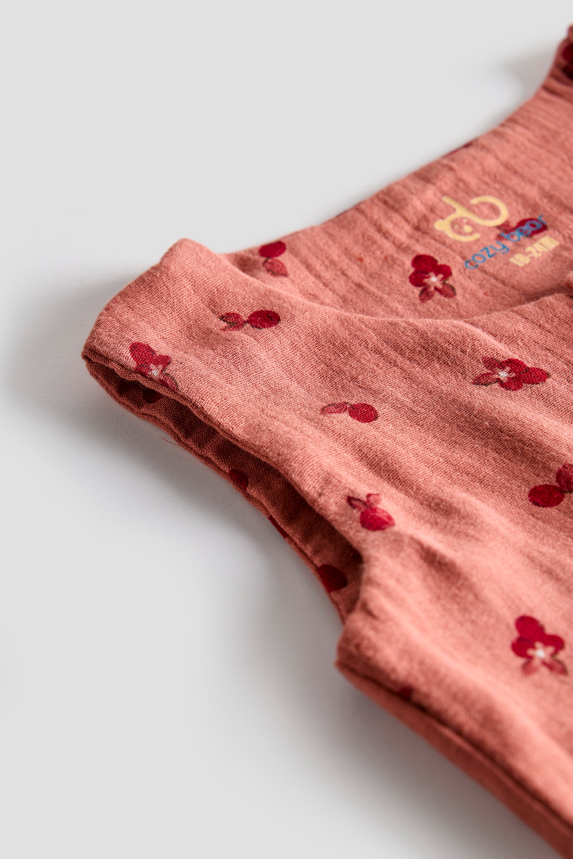 Pink fabric with red floral patterns on a light gray background