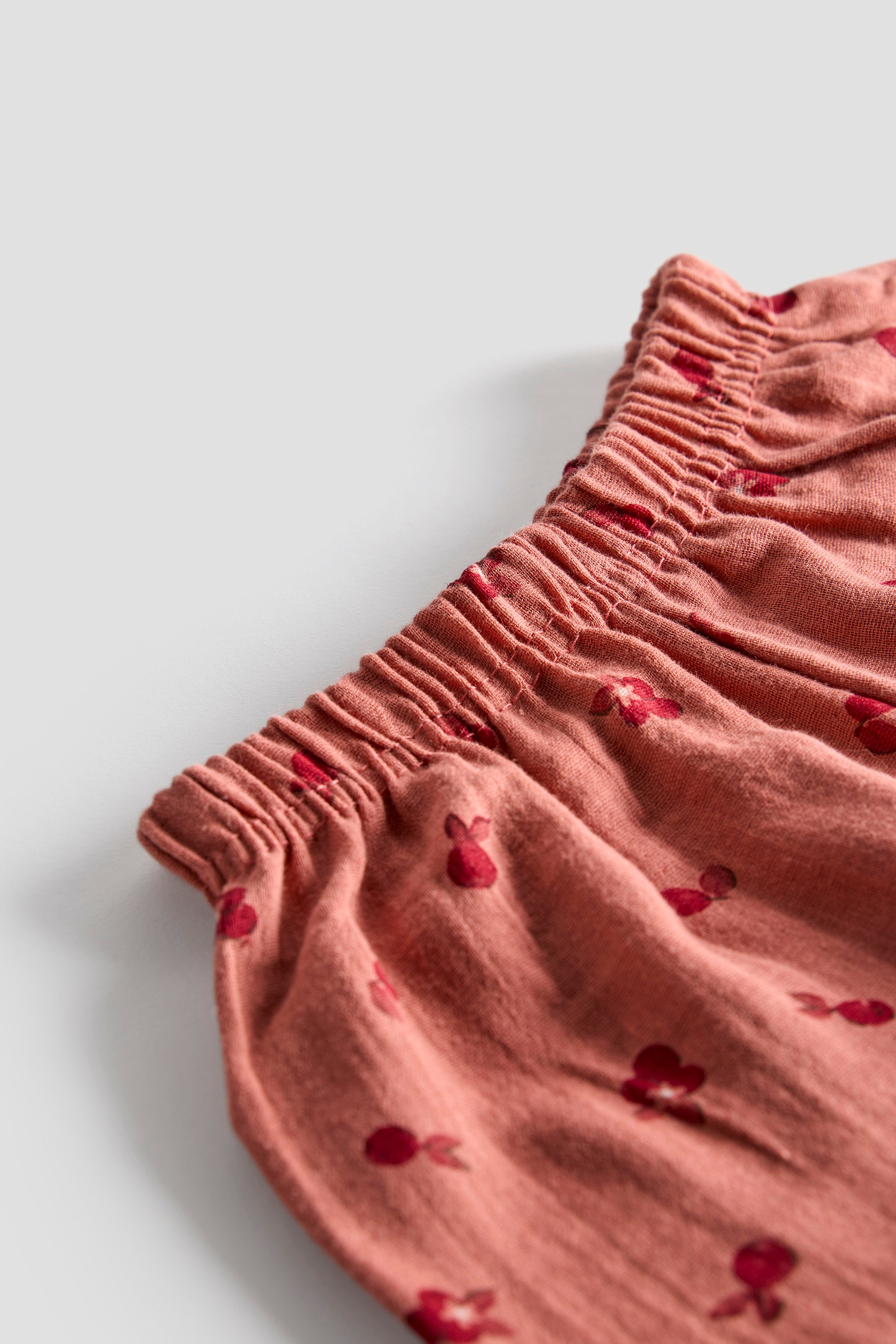 Pink fabric with red heart patterns on a light gray background
