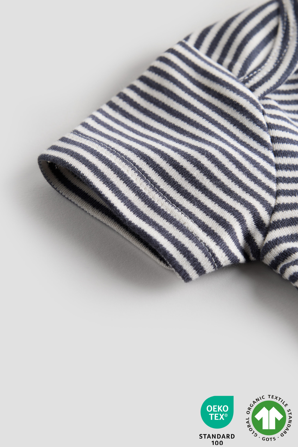 Close-up of a striped fabric with a visible Oeko-Tex Standard 100 label on a light gray background.