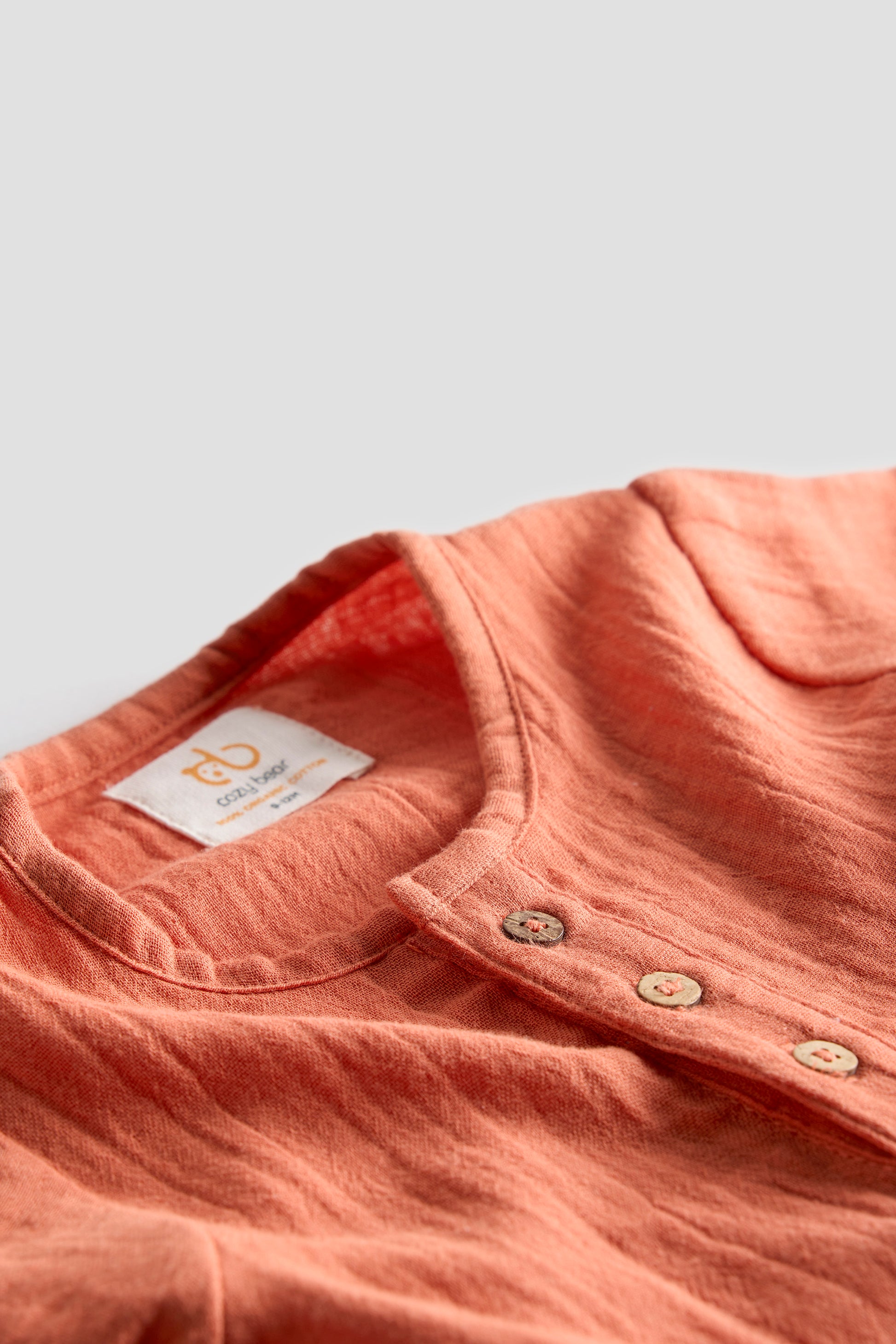Close-up of a pink shirt with a label on a light gray background
