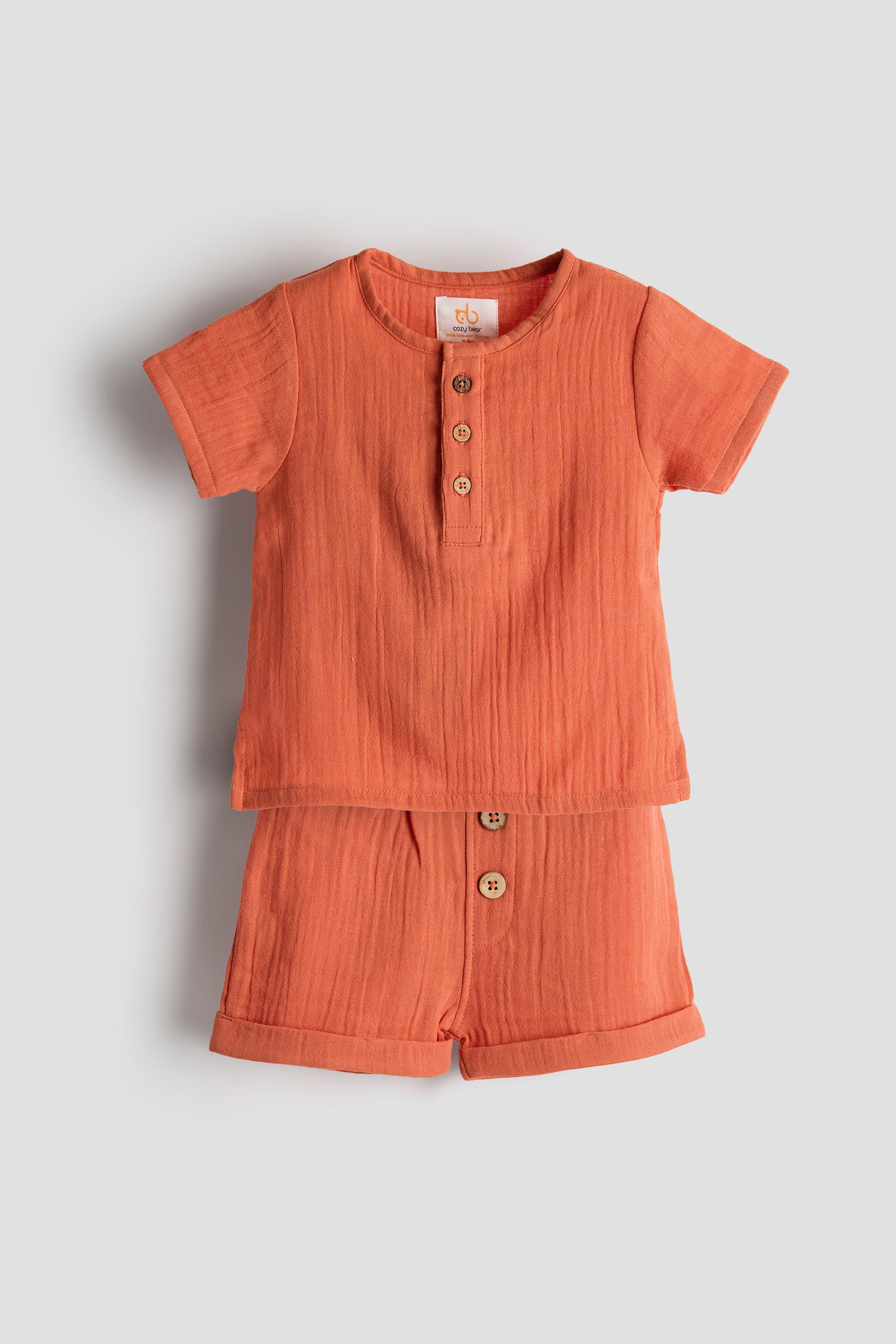 Children's orange outfit with buttons on a light gray background