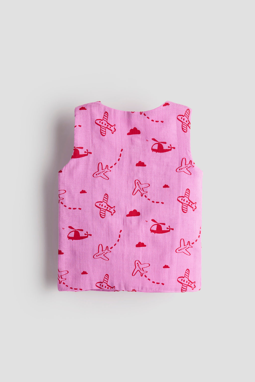 Folded pink blanket with red airplane and helicopter patterns on a light gray background