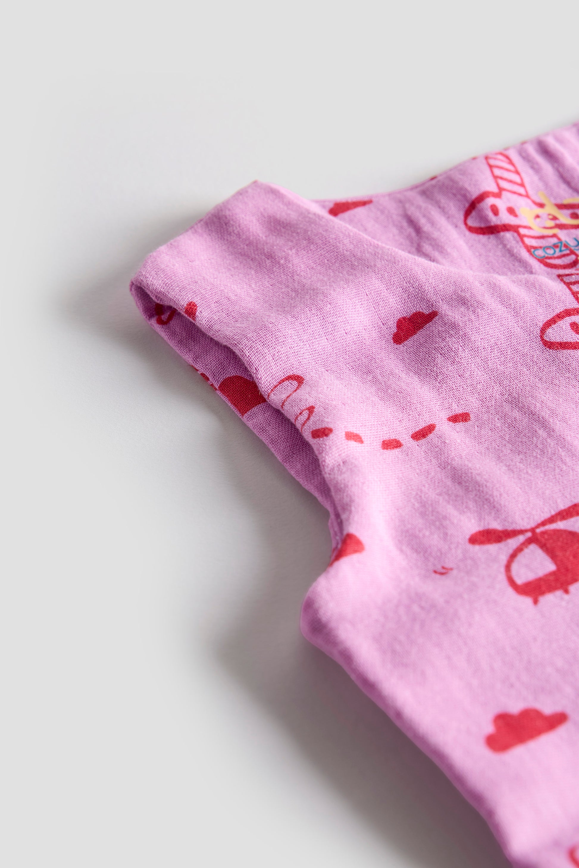 Close-up of a pink fabric with red heart patterns on a light gray background