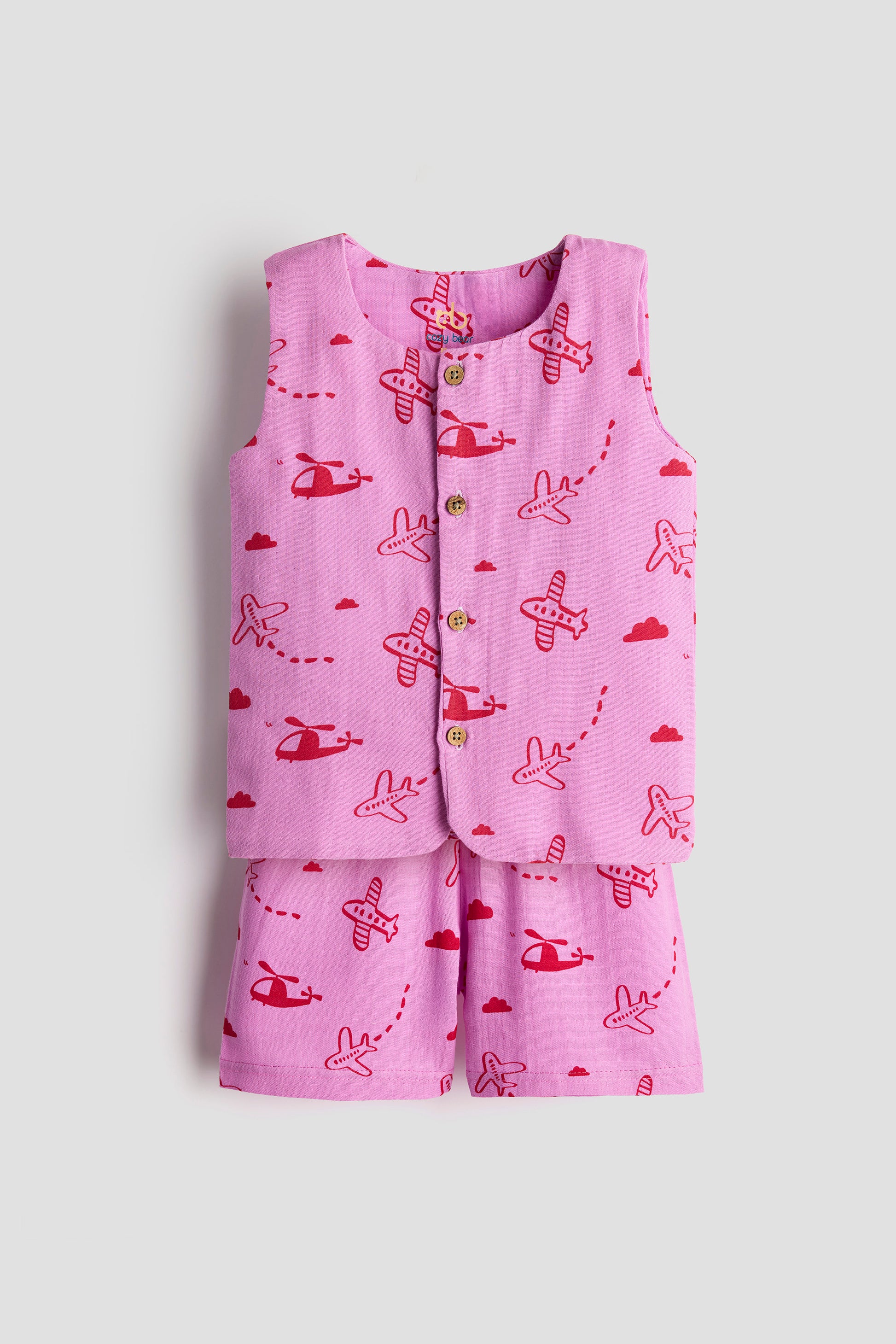 Pink children's outfit with airplane pattern on a light gray background