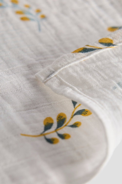 Close-up of a white fabric with embroidered yellow flowers on a light gray background