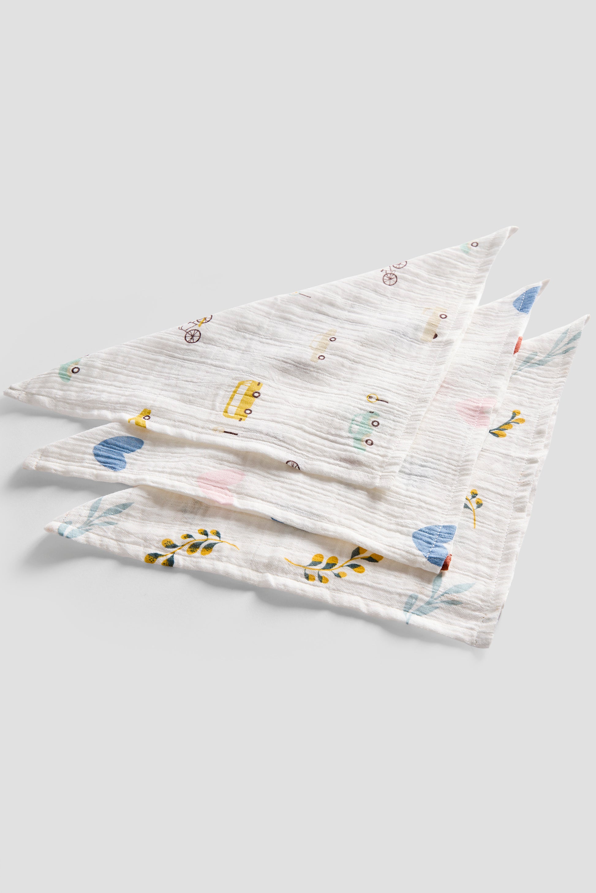 Set of three patterned baby bibs on a light gray background