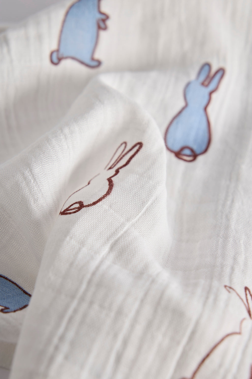 Close-up of white fabric with embroidered bunny designs.