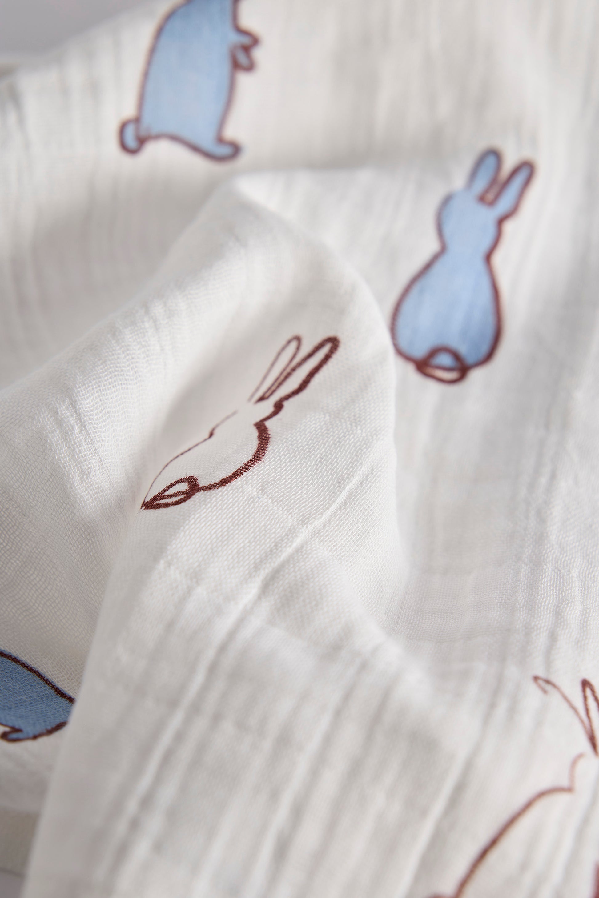 Close-up of white fabric with embroidered bunny designs.