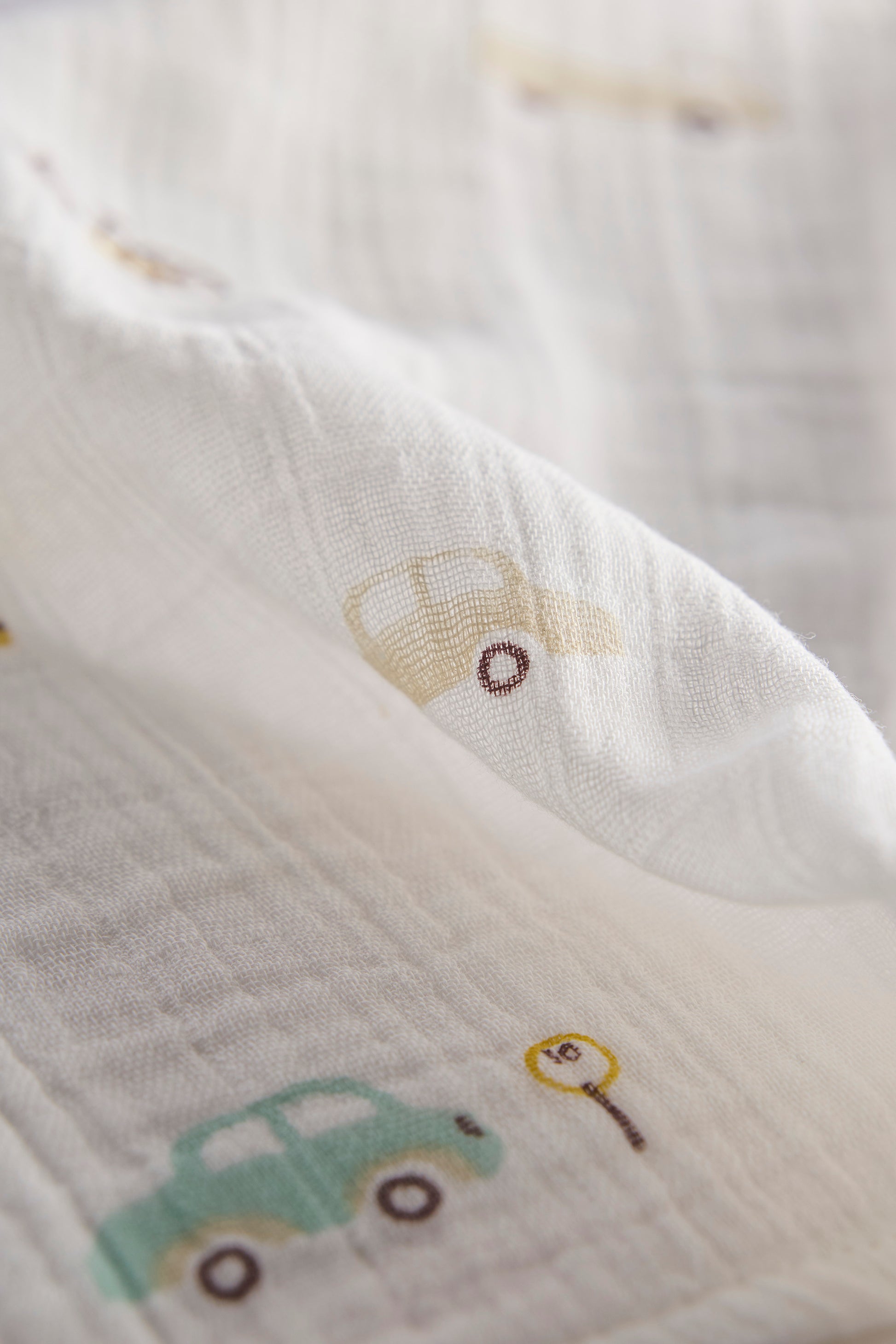 Close-up of a soft fabric with embroidered car designs on a light background