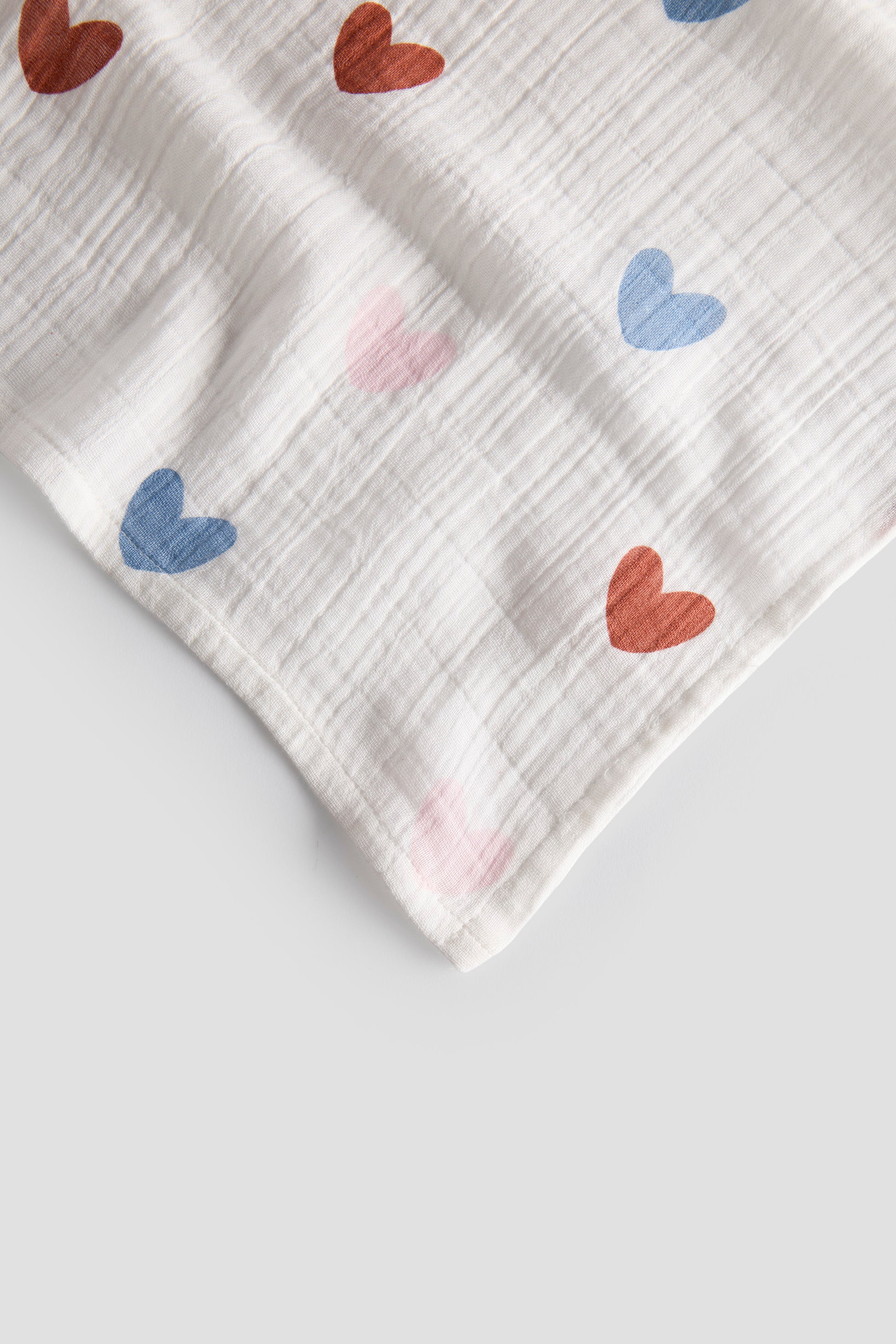 White fabric with red and blue heart patterns on a light gray background