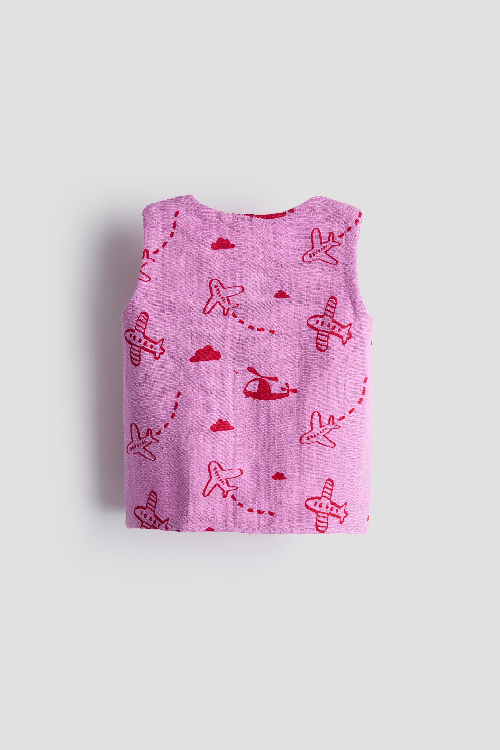 Folded pink fabric with red airplane patterns on a light gray background