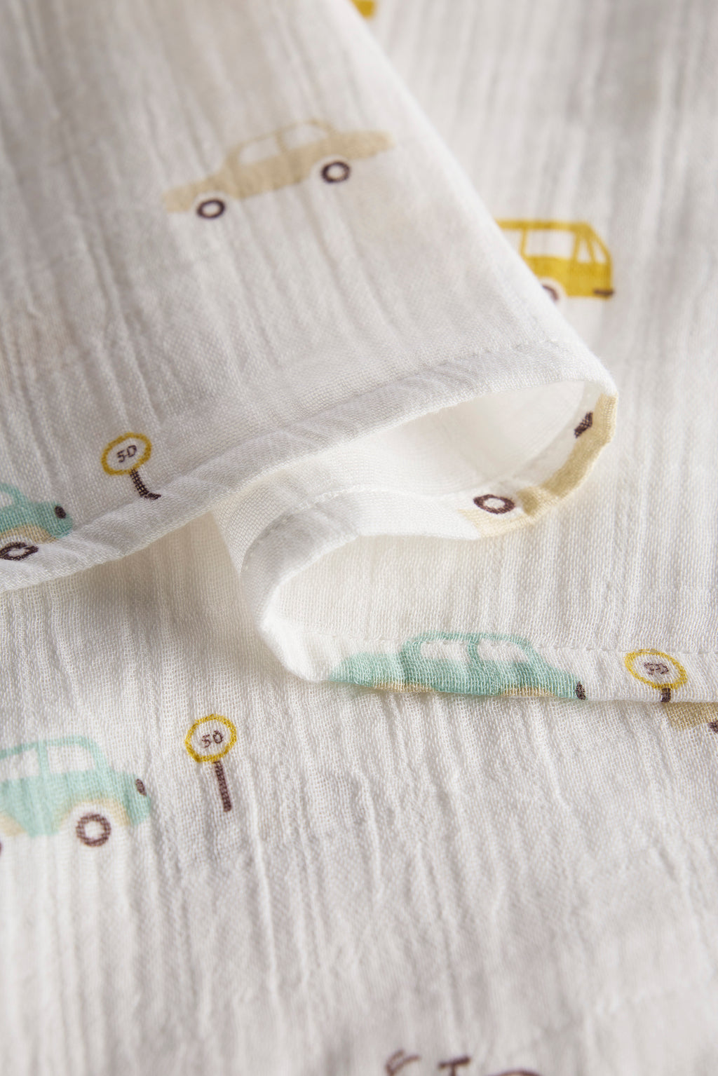 Close-up of white fabric with small vehicle patterns, including cars and trucks.