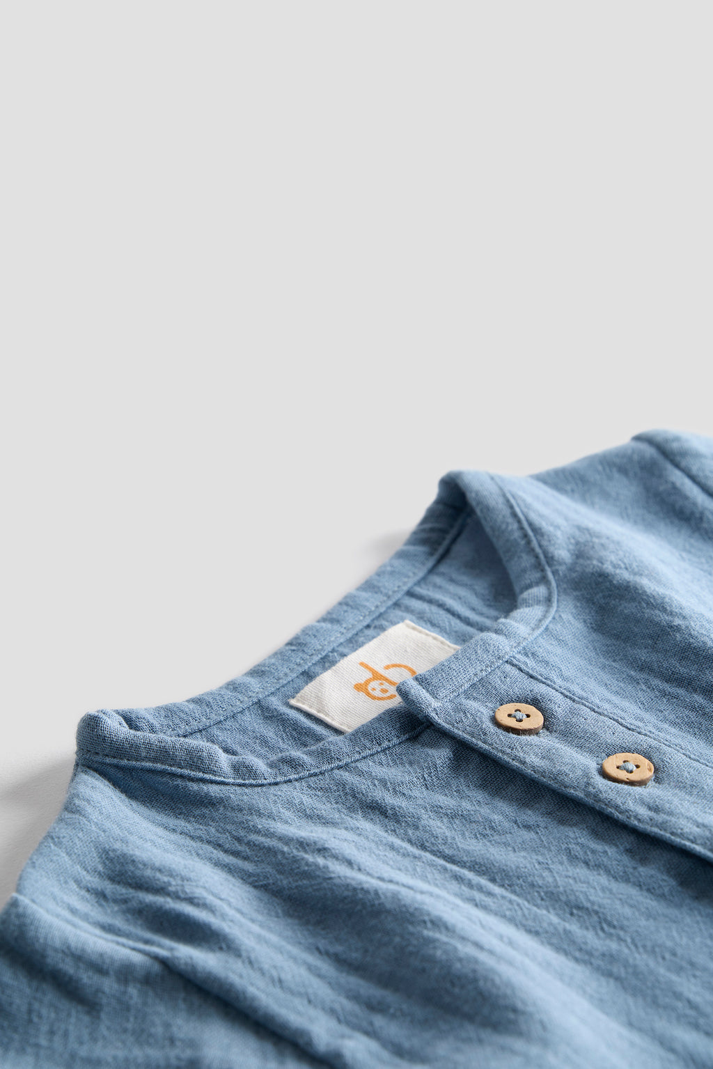 Close-up of a blue garment with a brand label on a light gray background