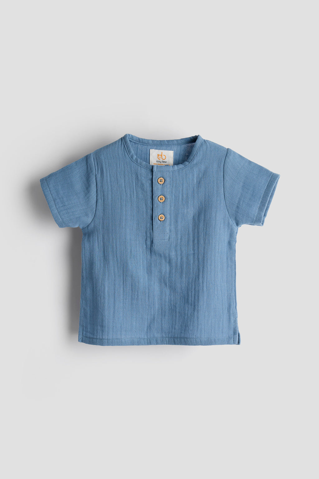 Blue baby shirt with buttons on a light gray background