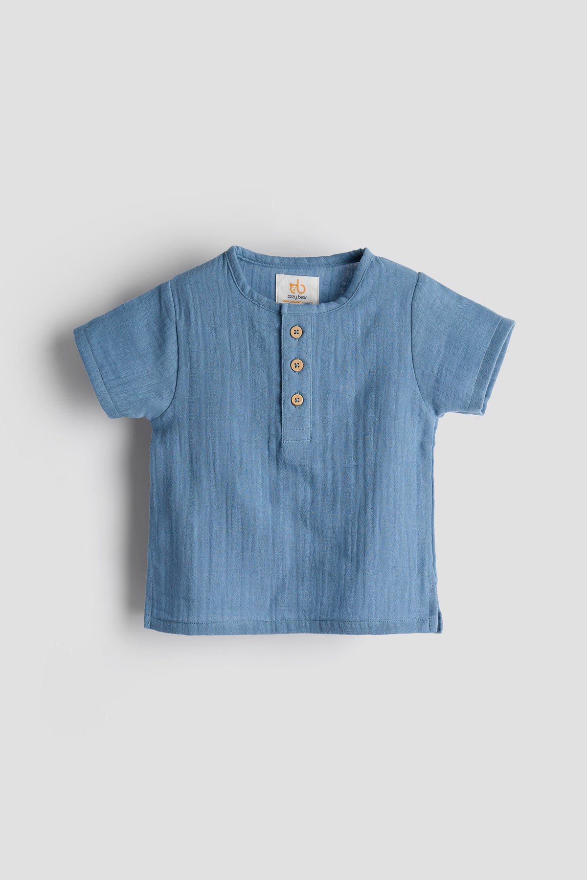 Blue baby shirt with buttons on a light gray background