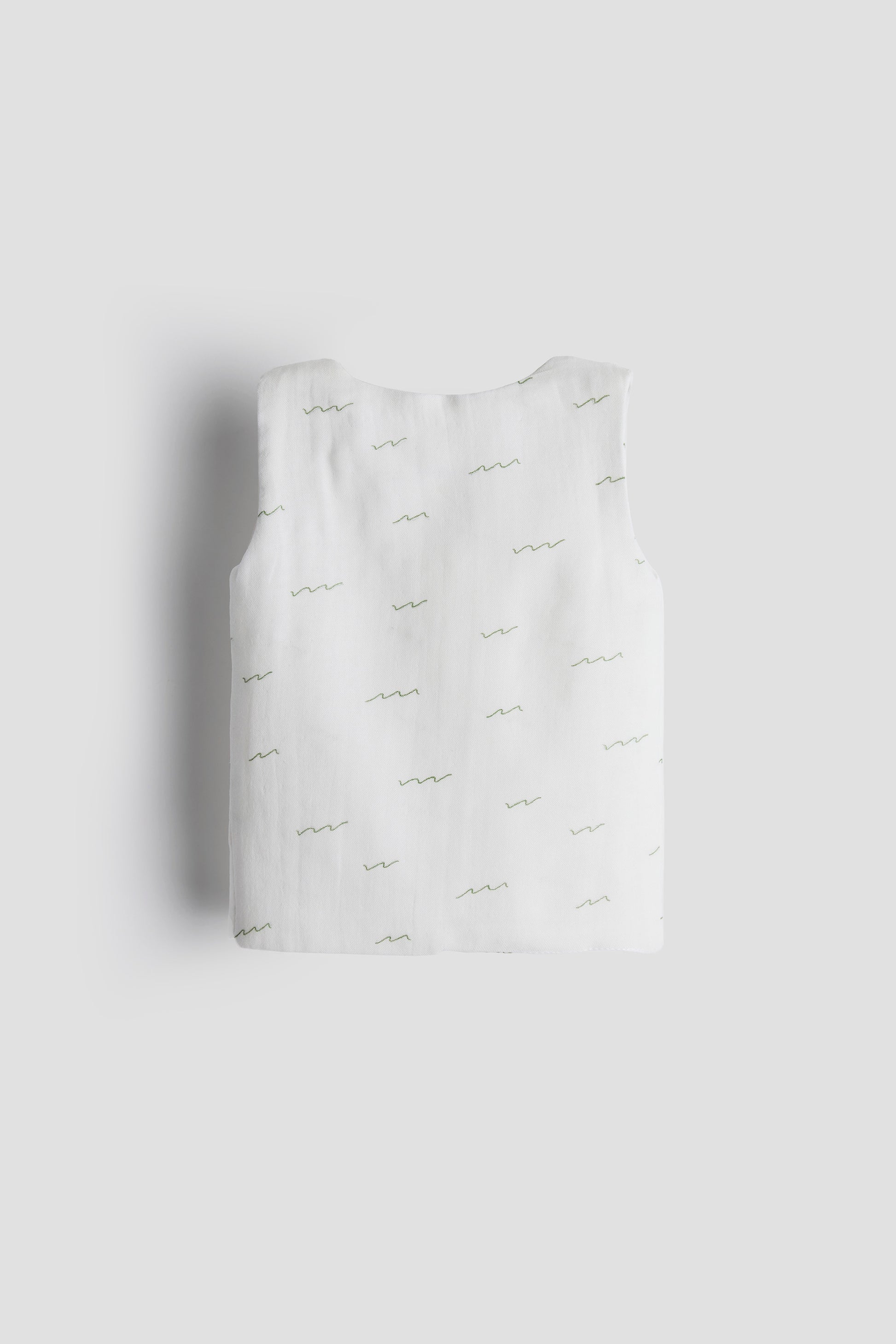 White tank top with thin straps on a light gray background