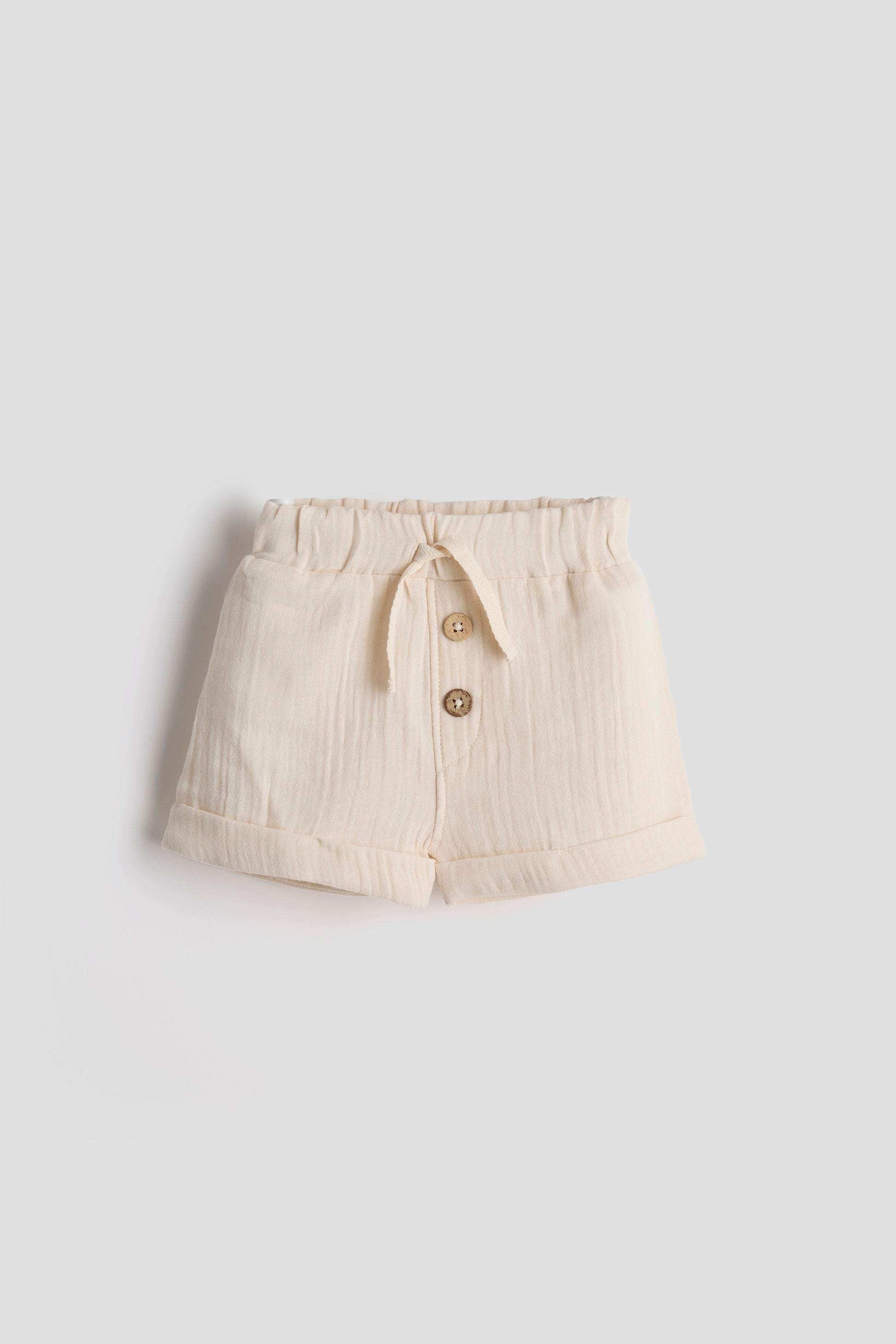 Beige shorts with buttons on a light gray background