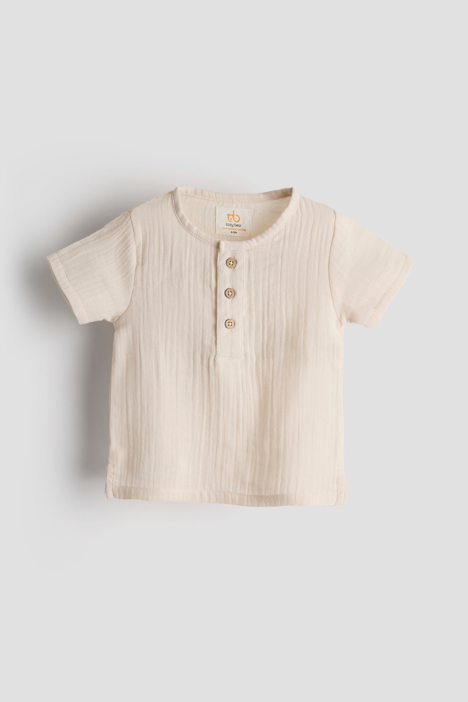 Beige baby shirt with buttons on a light gray background