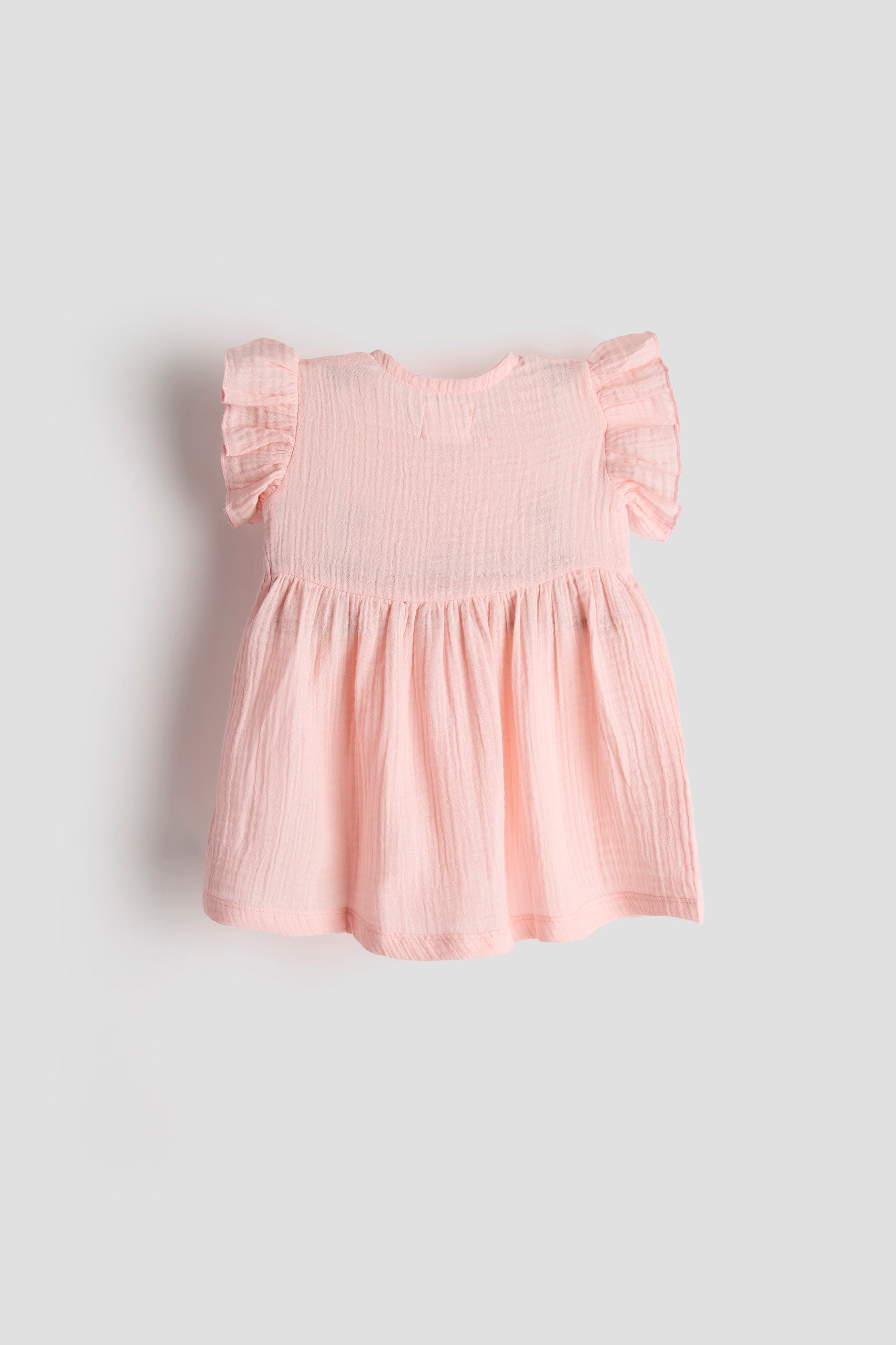 Pink baby dress with ruffled sleeves on a light gray background