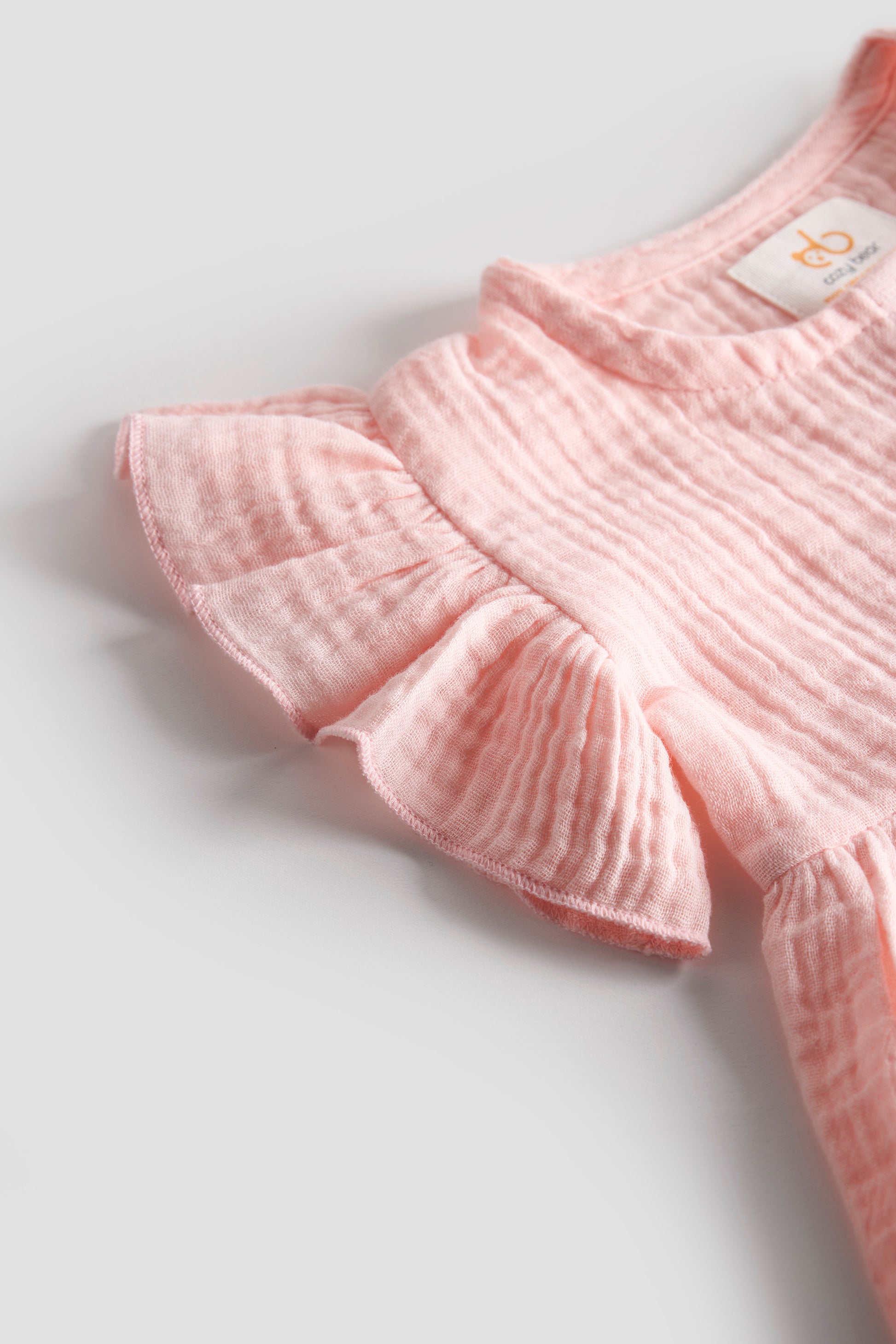 Pink ruffled garment on a light gray background