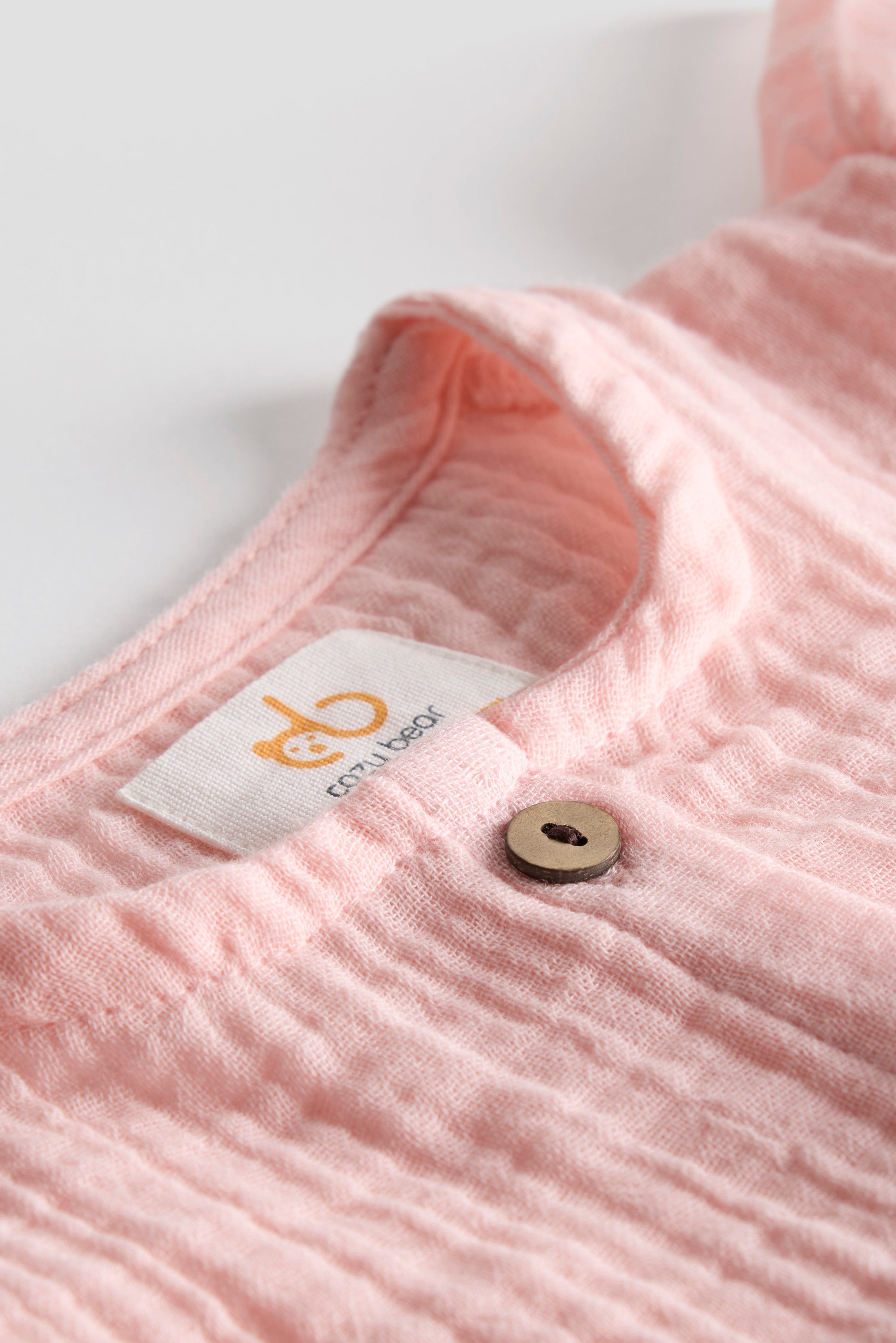 Close-up of a pink textured garment with a brand label on a white background