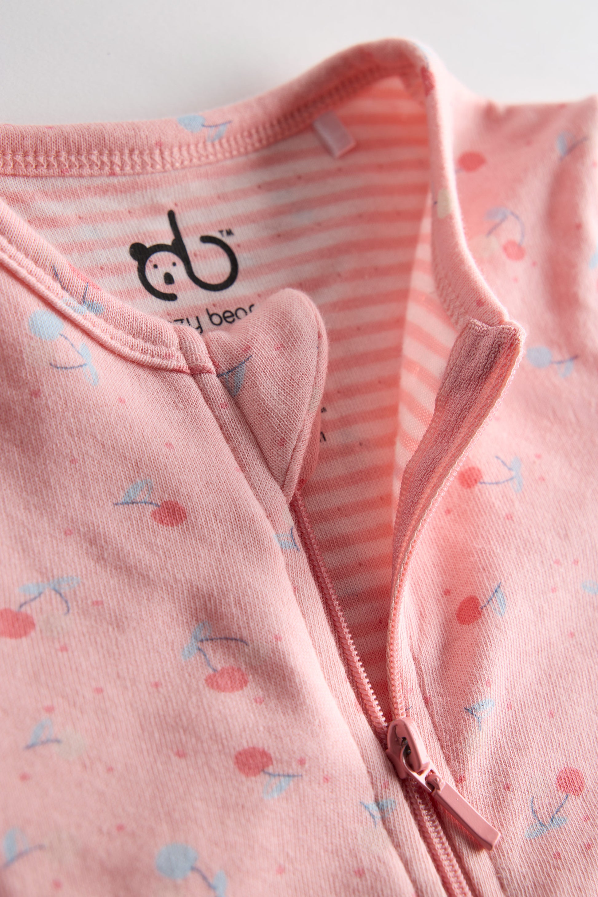 Pink organic cotton baby sleep suit with cherry print and zipper, certified safe and ultra-soft by Cozy Bear.