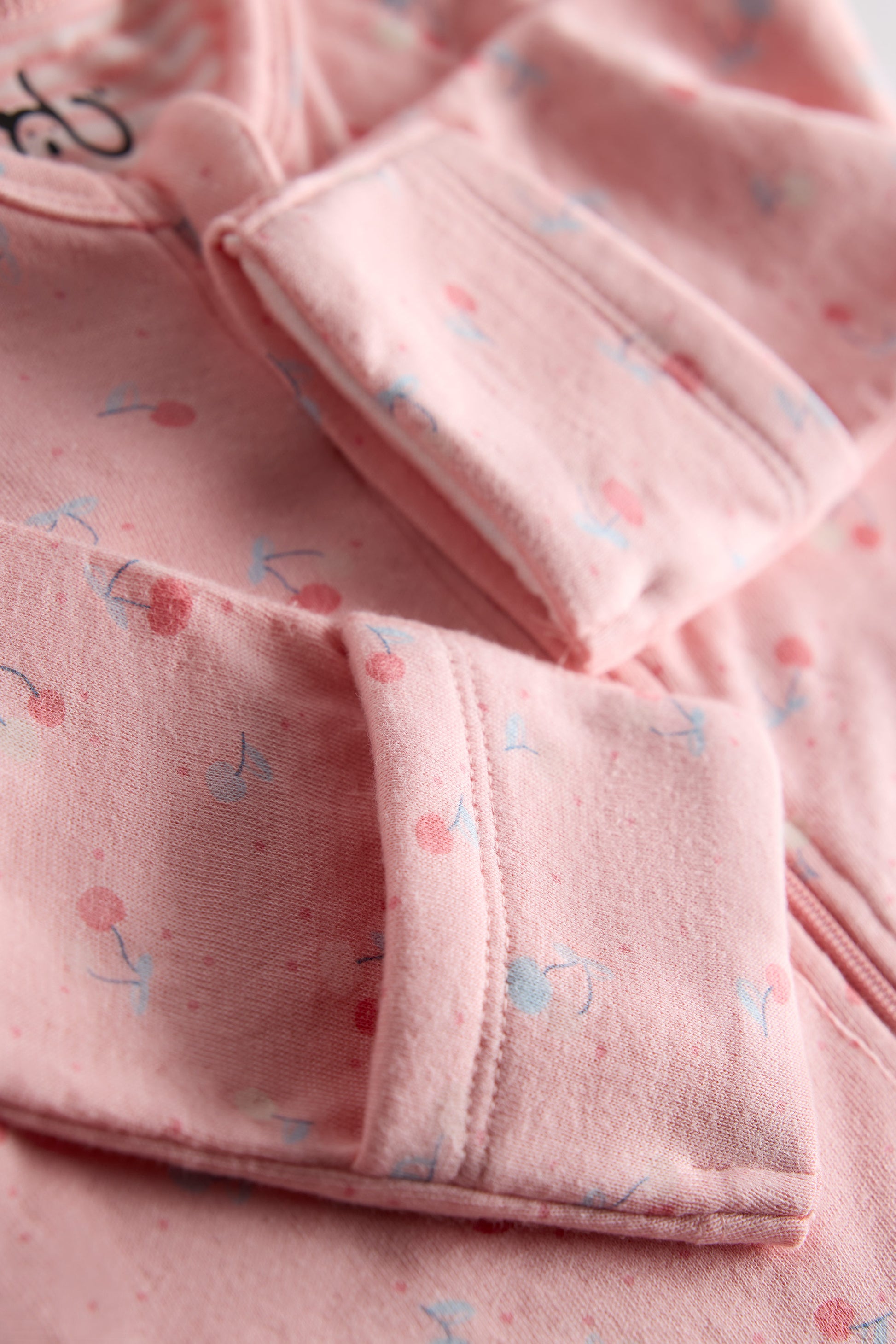 Close-up of pink fabric with small patterns, possibly from a garment.
