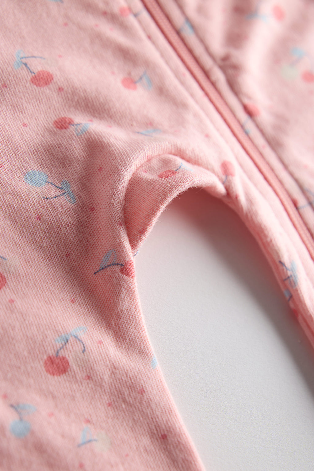 Close-up of pink fabric with cherry pattern on a white background