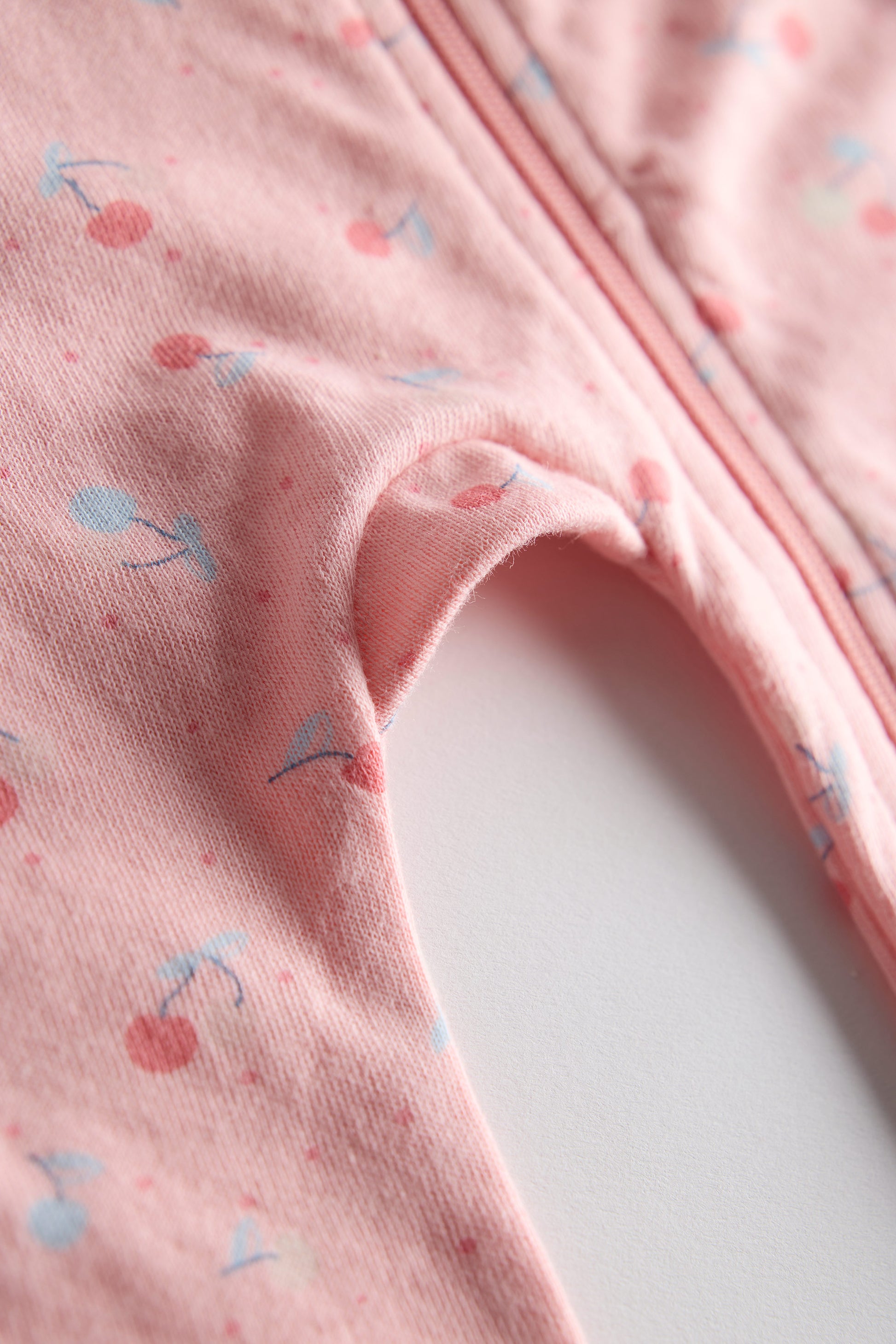 Close-up of pink fabric with cherry pattern on a white background