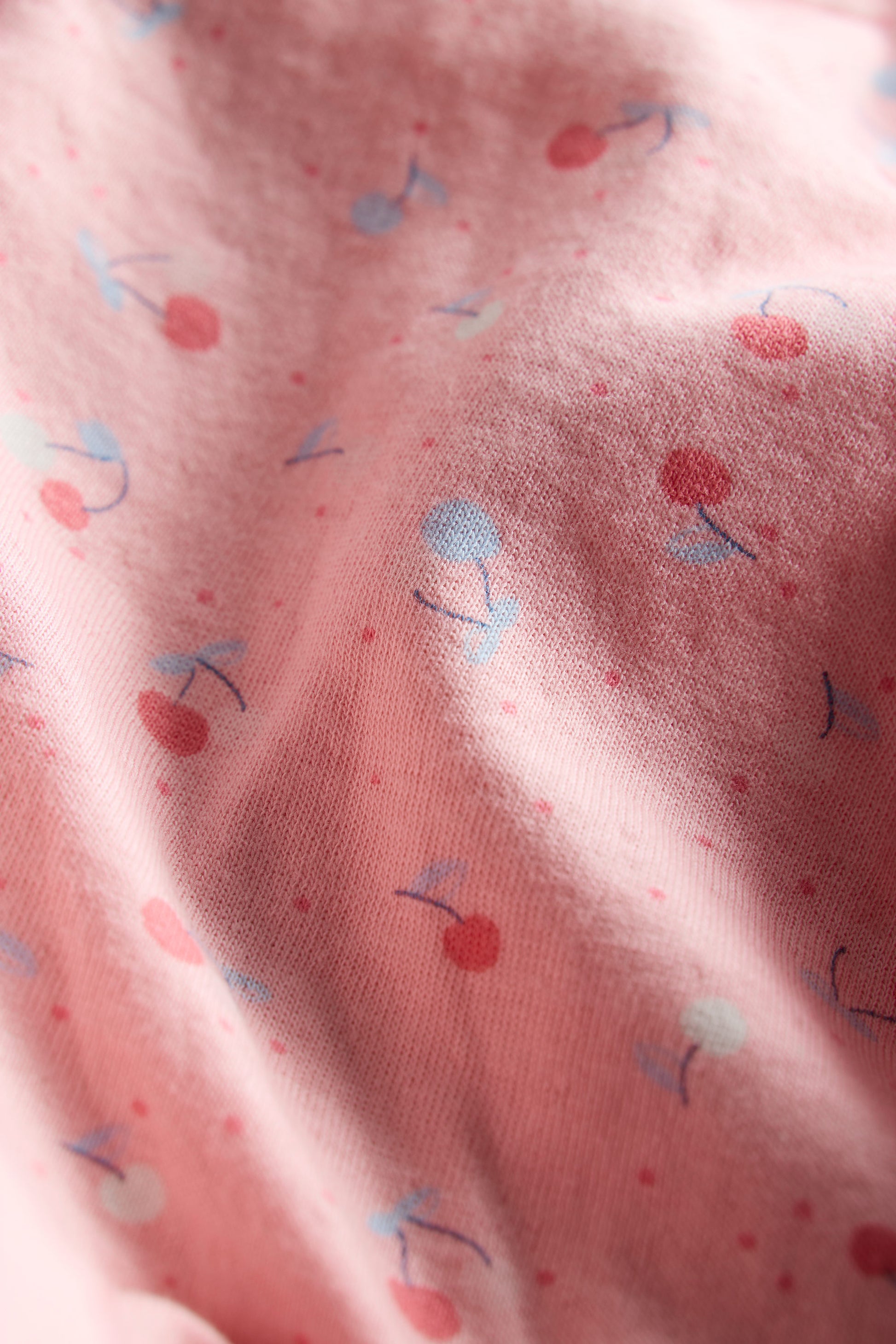 Close-up of pink fabric with small colorful patterns