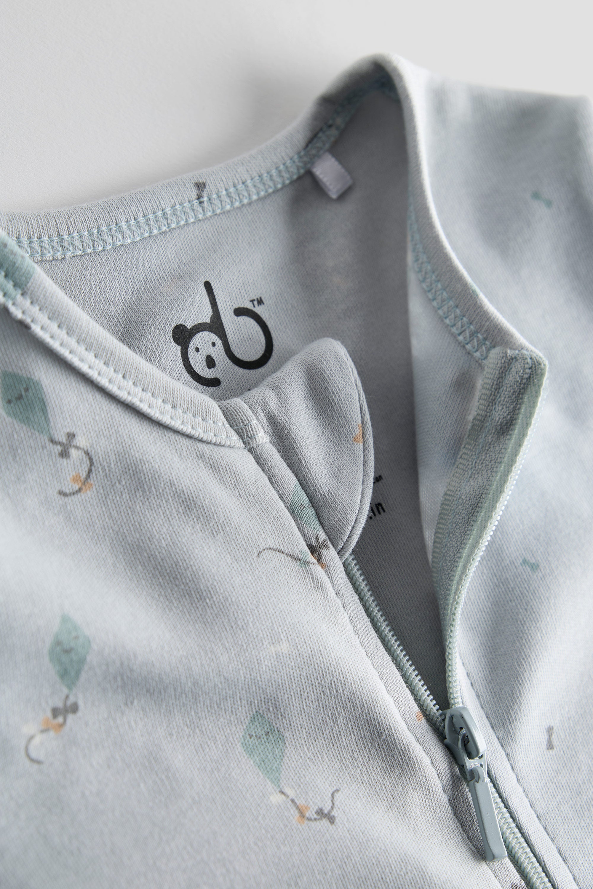 Light blue organic cotton baby sleep suit with kite print and zipper, GOTS certified and crafted by Cozy Bear.