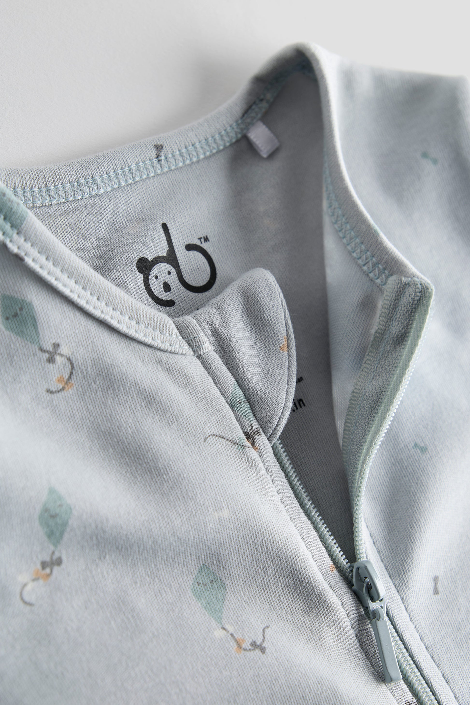 Light blue organic cotton baby sleep suit with kite print and zipper, GOTS certified and crafted by Cozy Bear.
