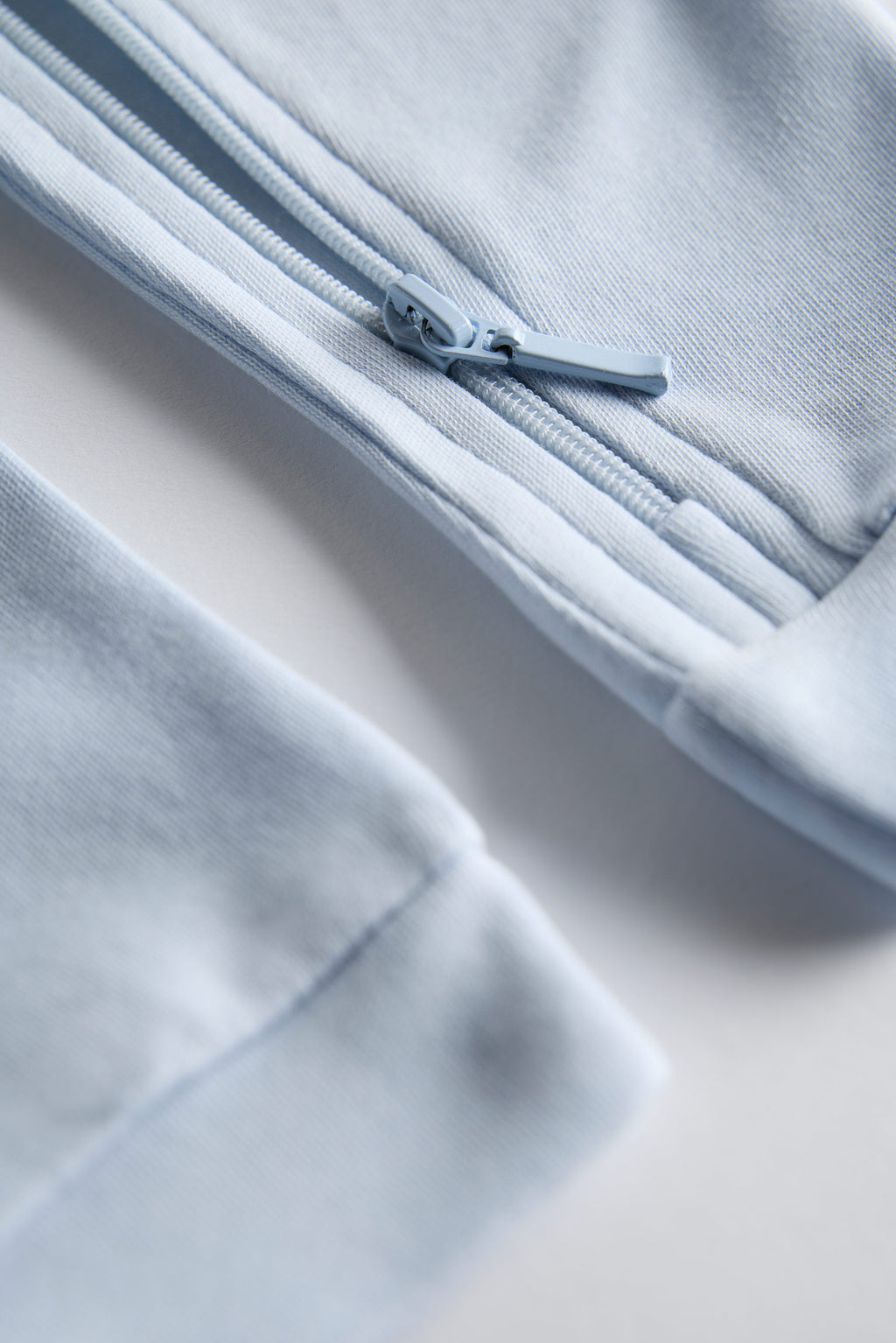 Close-up of a light blue fabric with a zipper on a neutral background
