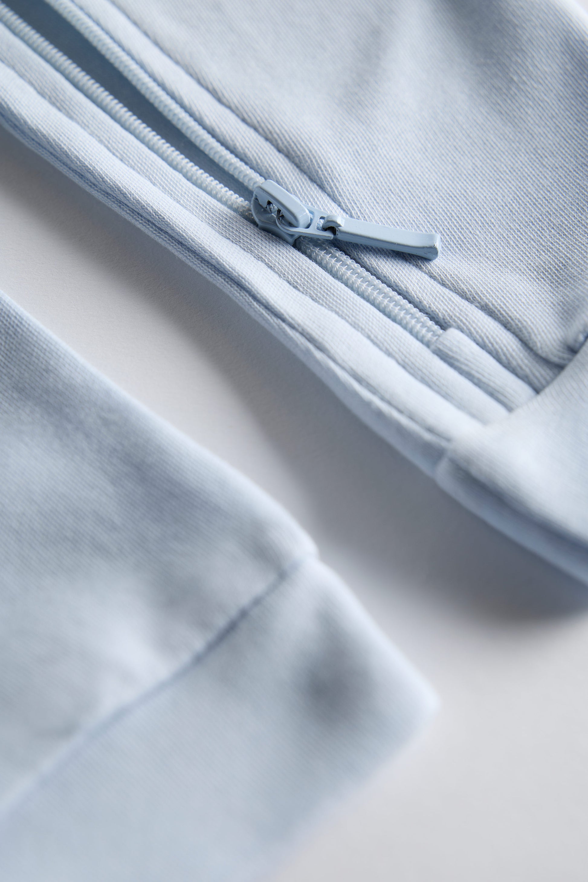 Close-up of a light blue fabric with a zipper on a neutral background