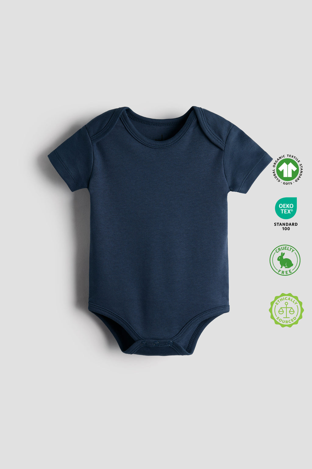 Navy blue baby bodysuit on a light gray background with OEKO-TEX and GOTS labels.