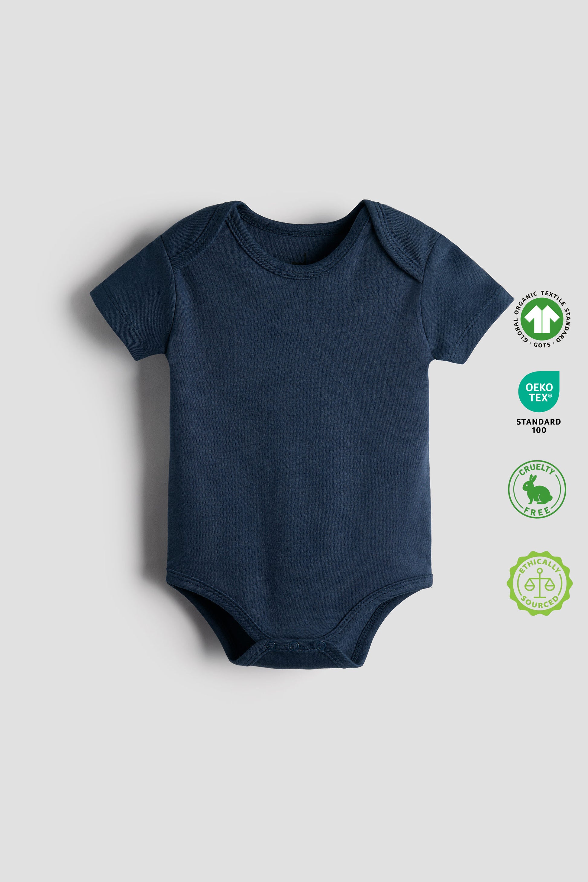 Navy blue baby bodysuit on a light gray background with OEKO-TEX and GOTS labels.